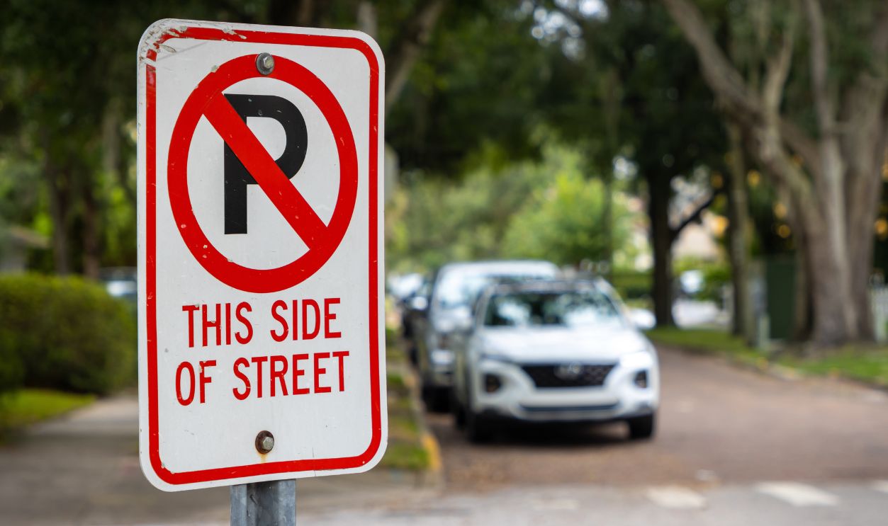 No parking sign with cars on side of city street