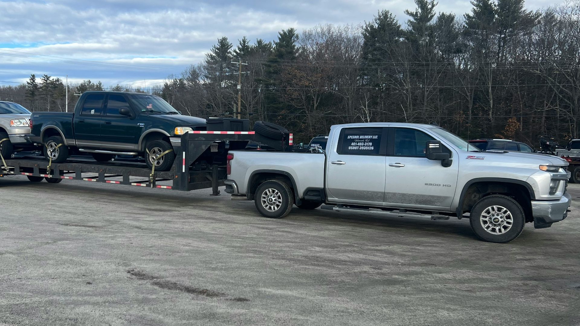 a tow truck towing a silver truck in a parking lot