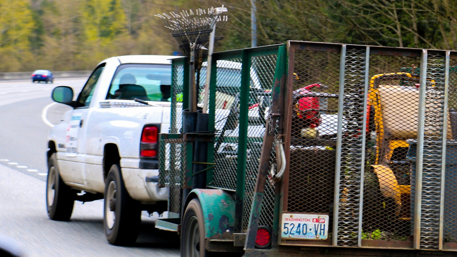 a white truck driving down a road next to a forest