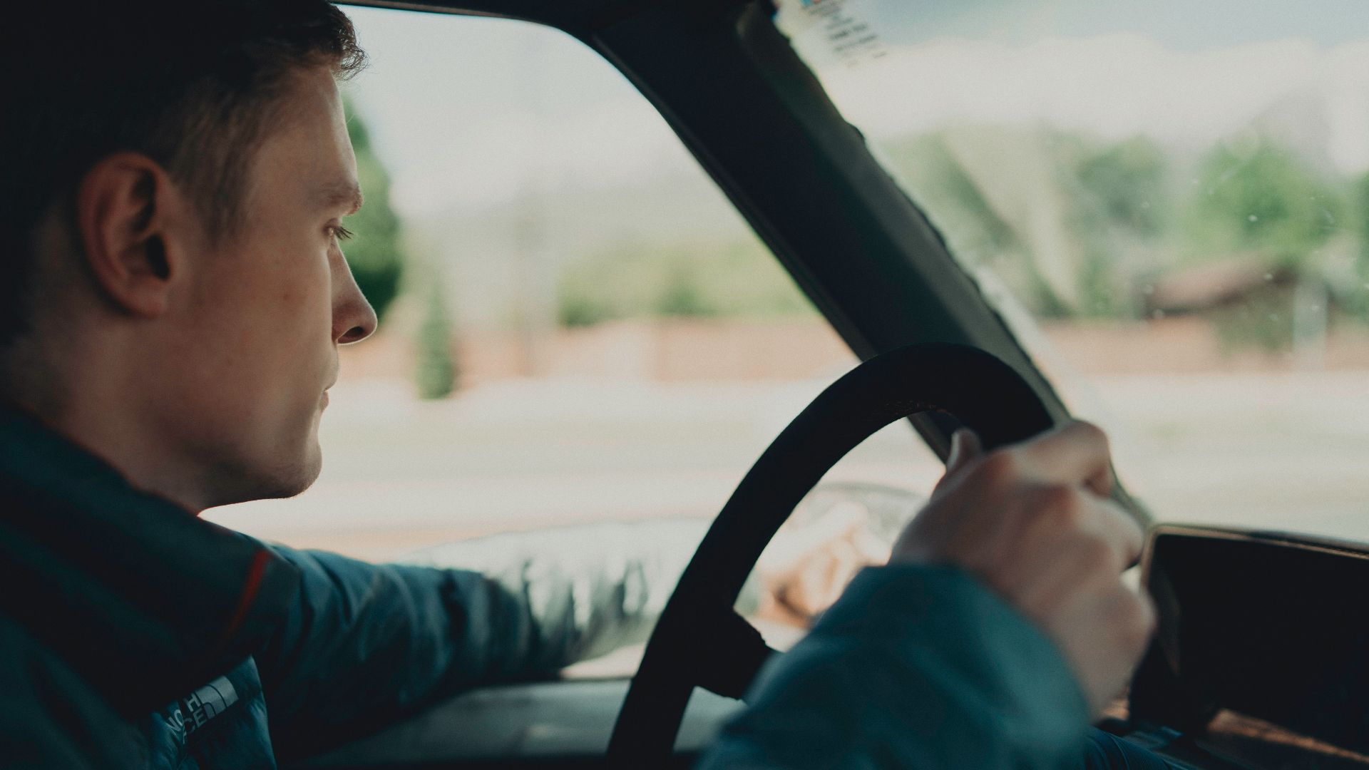 man holding steering wheel and wing mirror