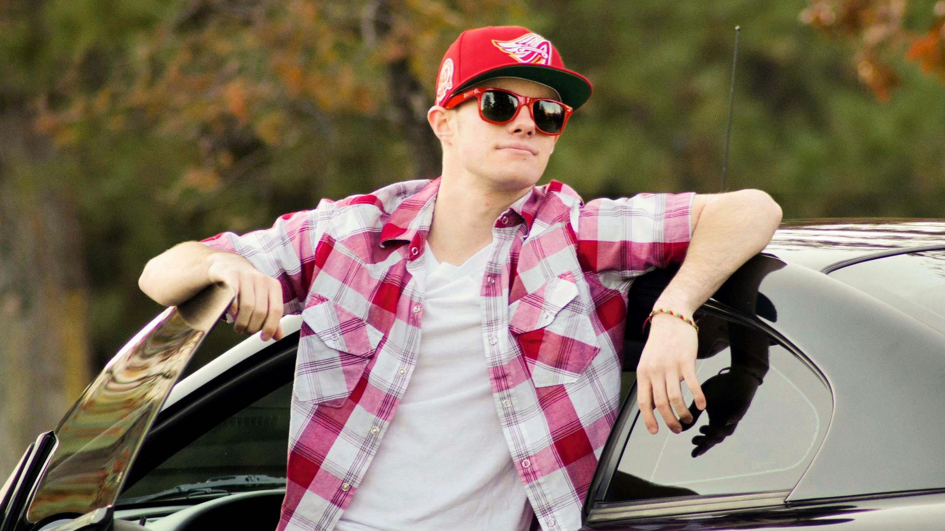 a man in a red and white checkered shirt leaning out of a car