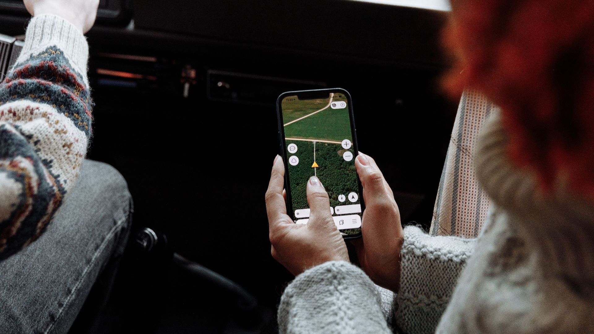 Two people using a navigation app on a smartphone during a road trip