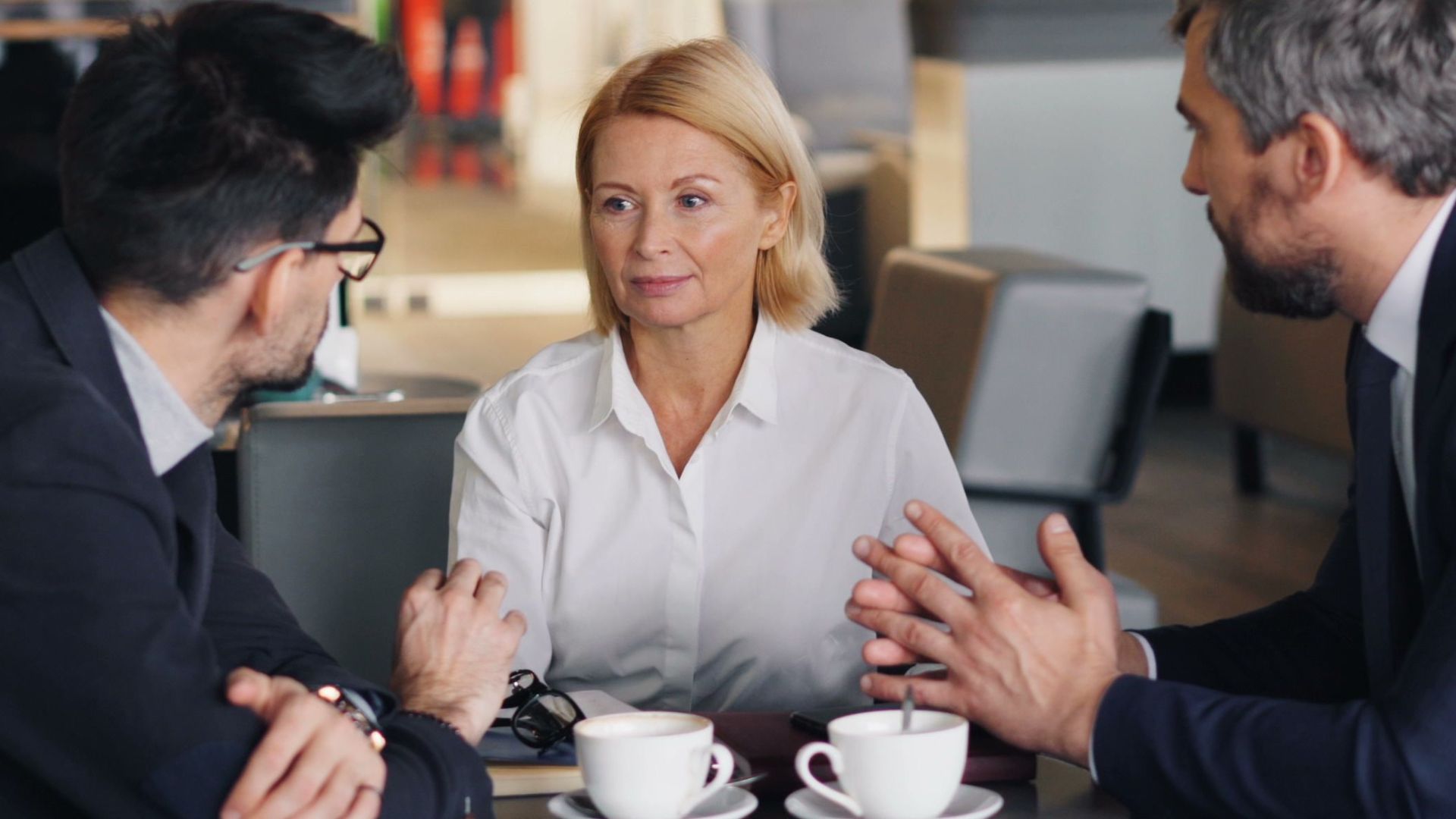 Business professionals engaged in a meeting at a cafe setting, discussing ideas.