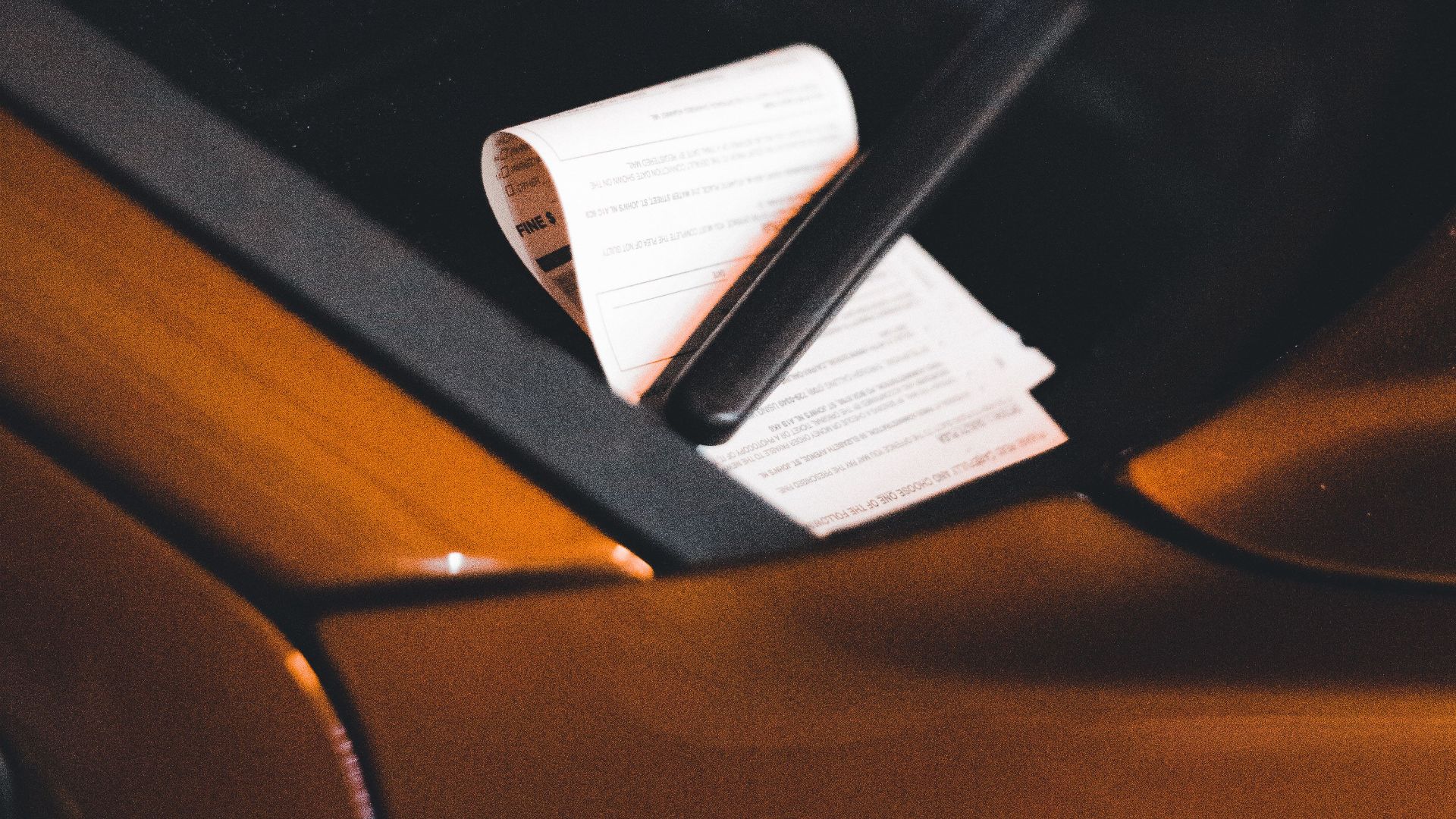 Close-up of a parking ticket on a car windshield at night, highlighting urban parking issues.