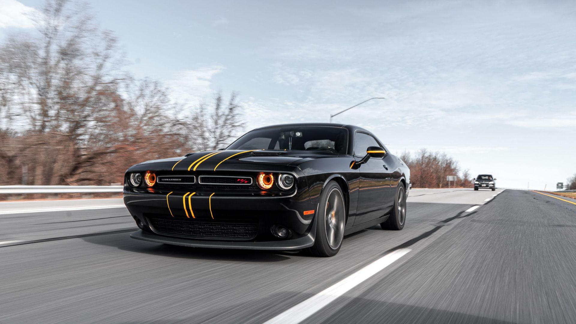 High-performance black car driving fast on a highway with dynamic motion blur.