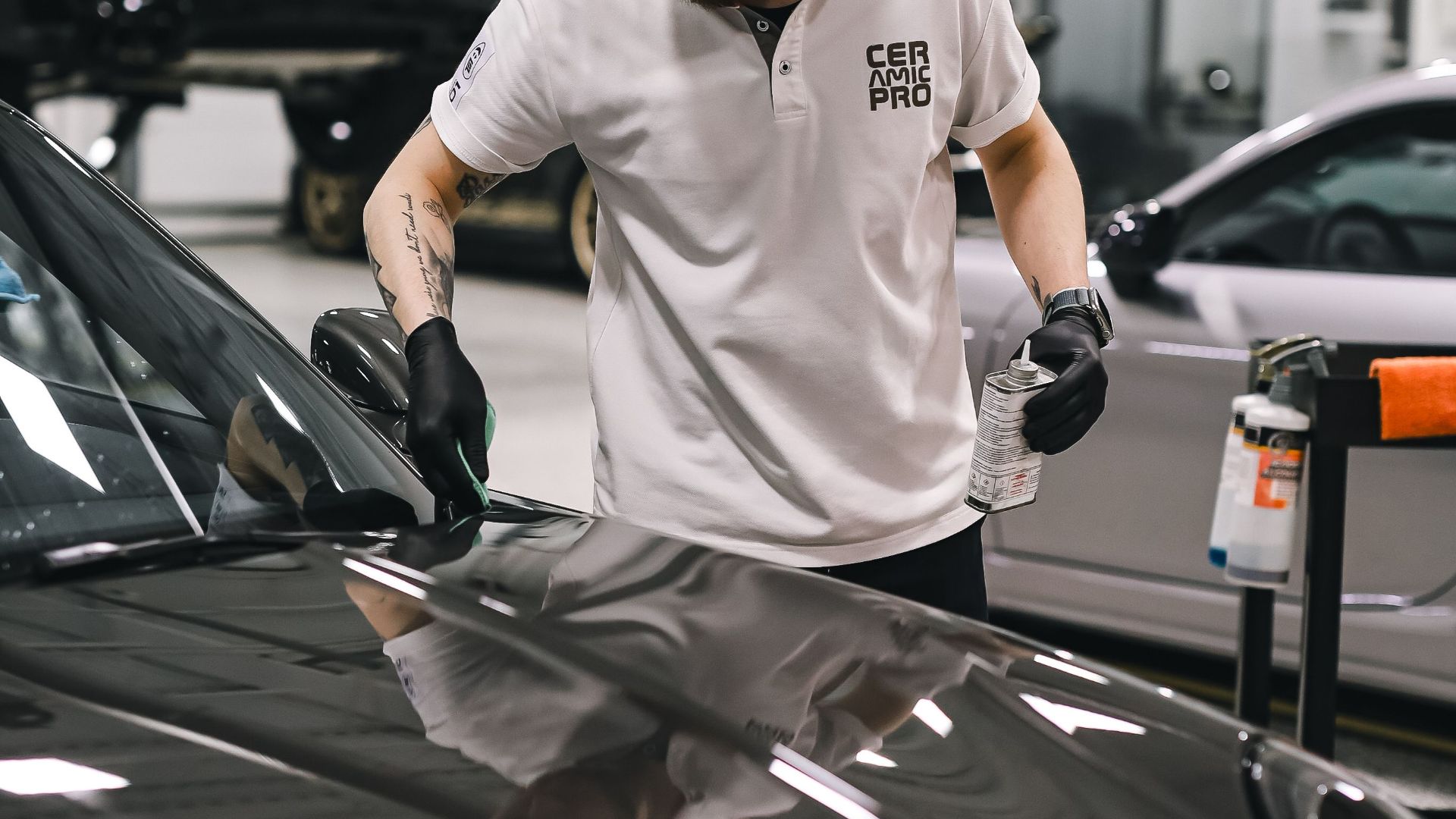 A dedicated employee expertly detailing a car hood in a clean, modern garage setting.