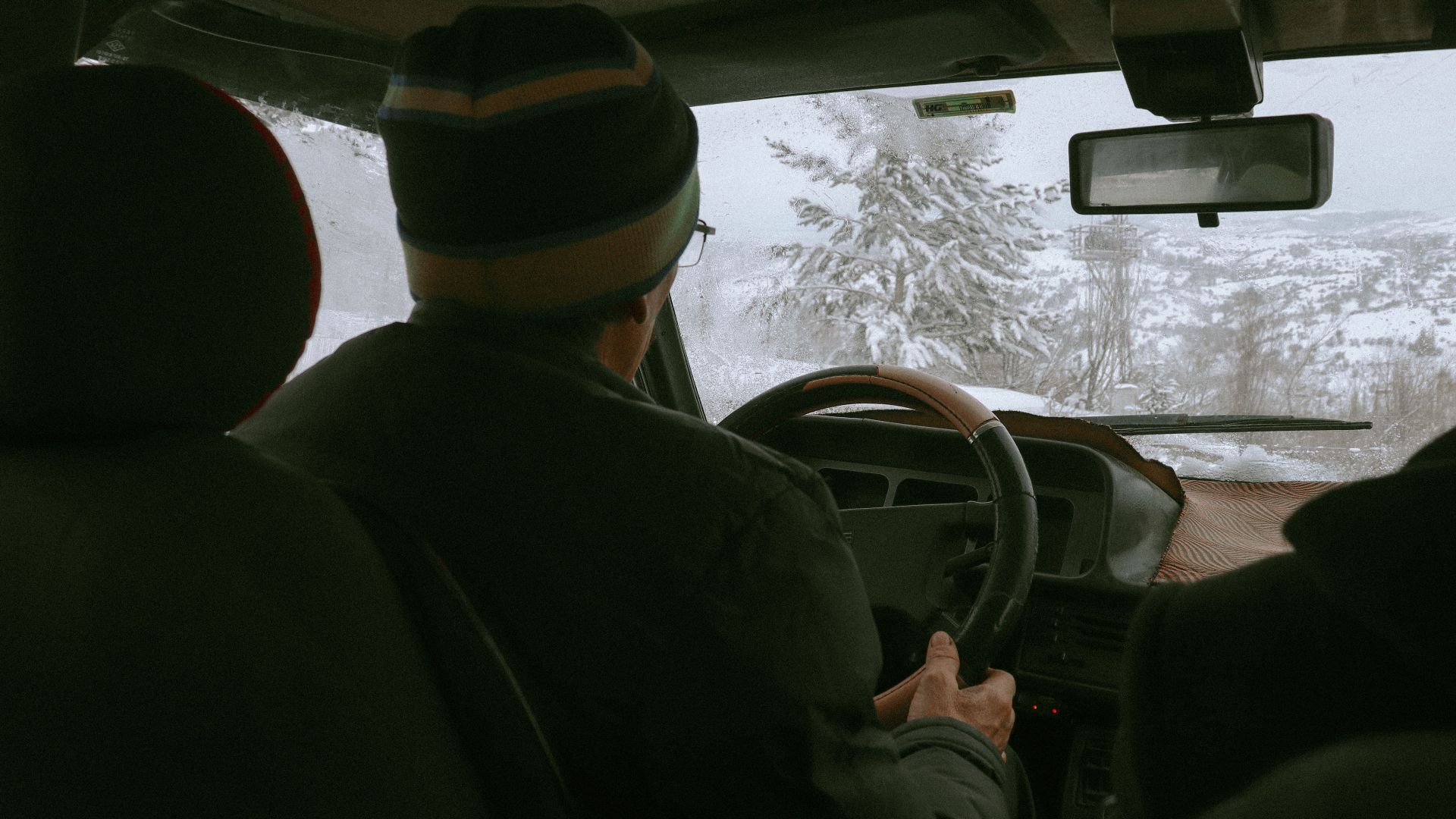 Driver navigating snowy winter landscape from vehicle's interior view.
