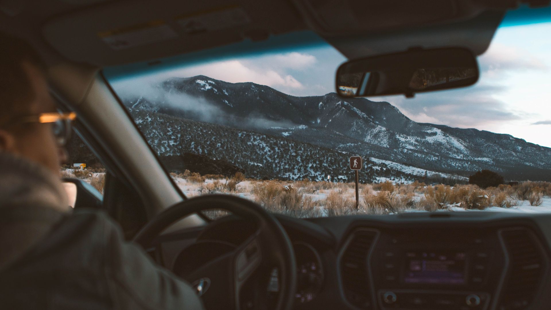View of a snowy mountain landscape from a car's interior during a winter road trip.