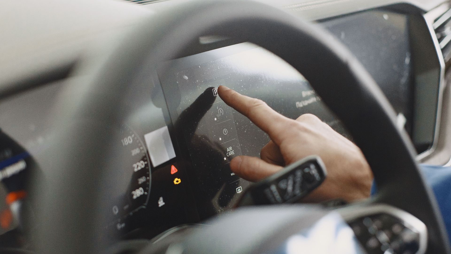 Close-up of a hand interacting with a car's digital dashboard. Modern technology and driving interface.