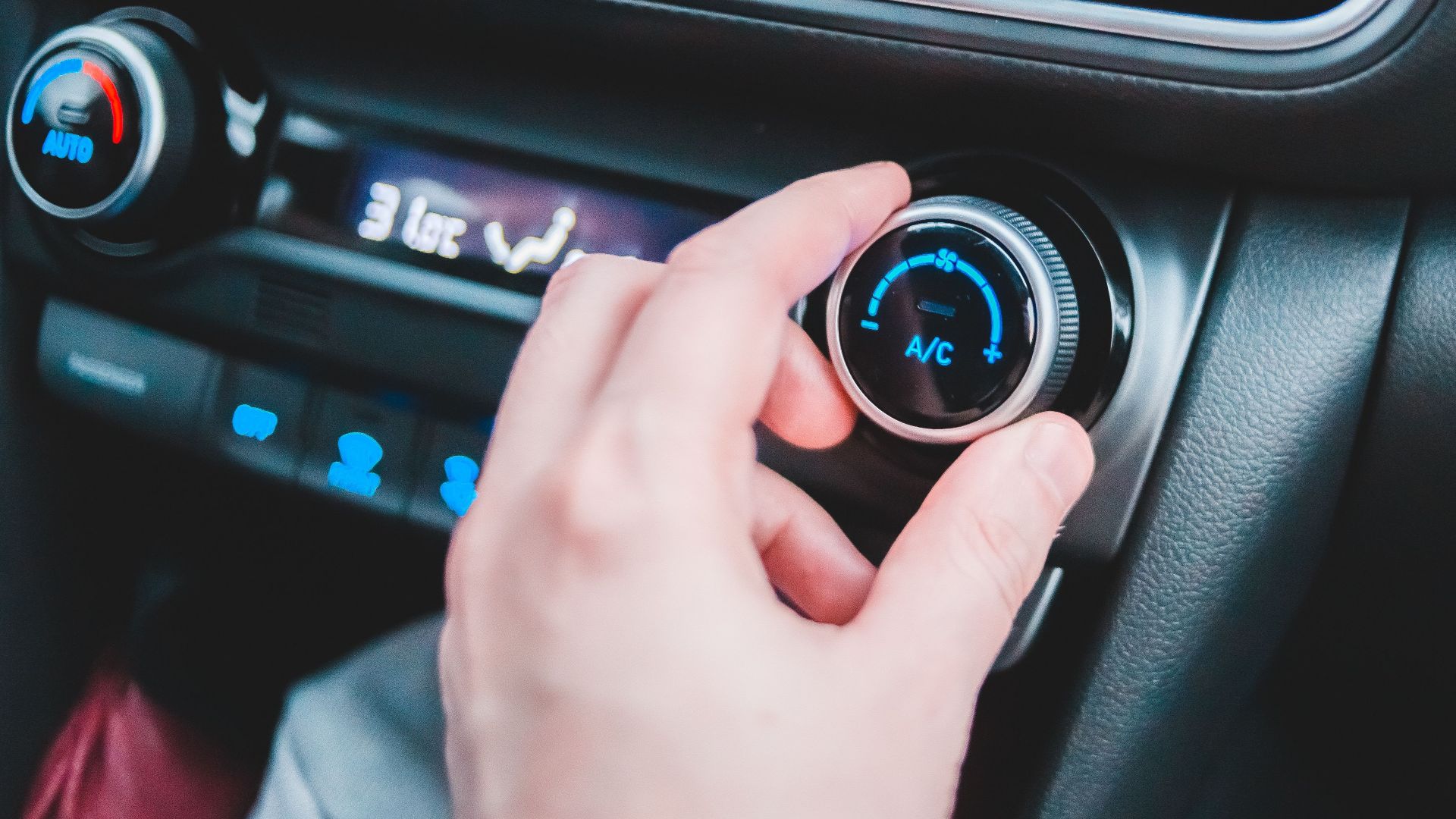 Crop anonymous person regulating temperature in car using controller on panel while sitting in car