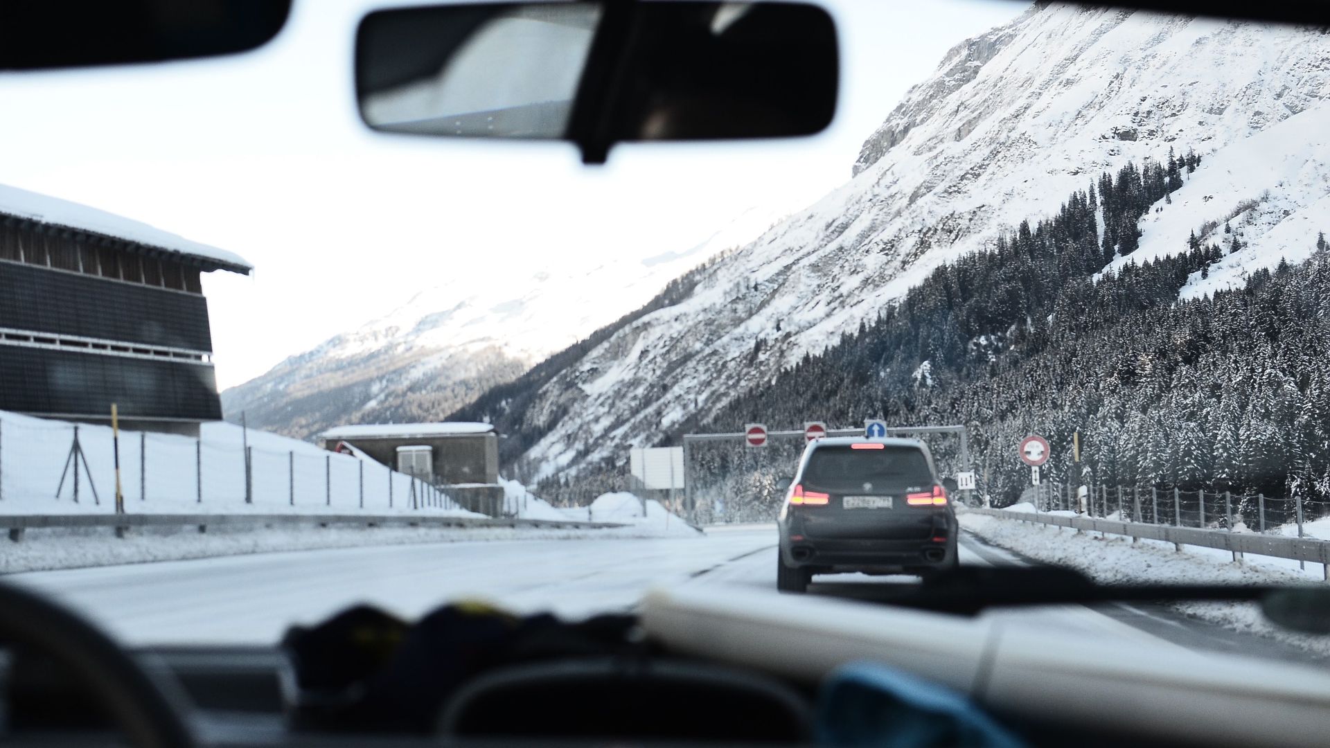 Experience a scenic winter drive through snow-covered Swiss Alps with breathtaking mountain views.
