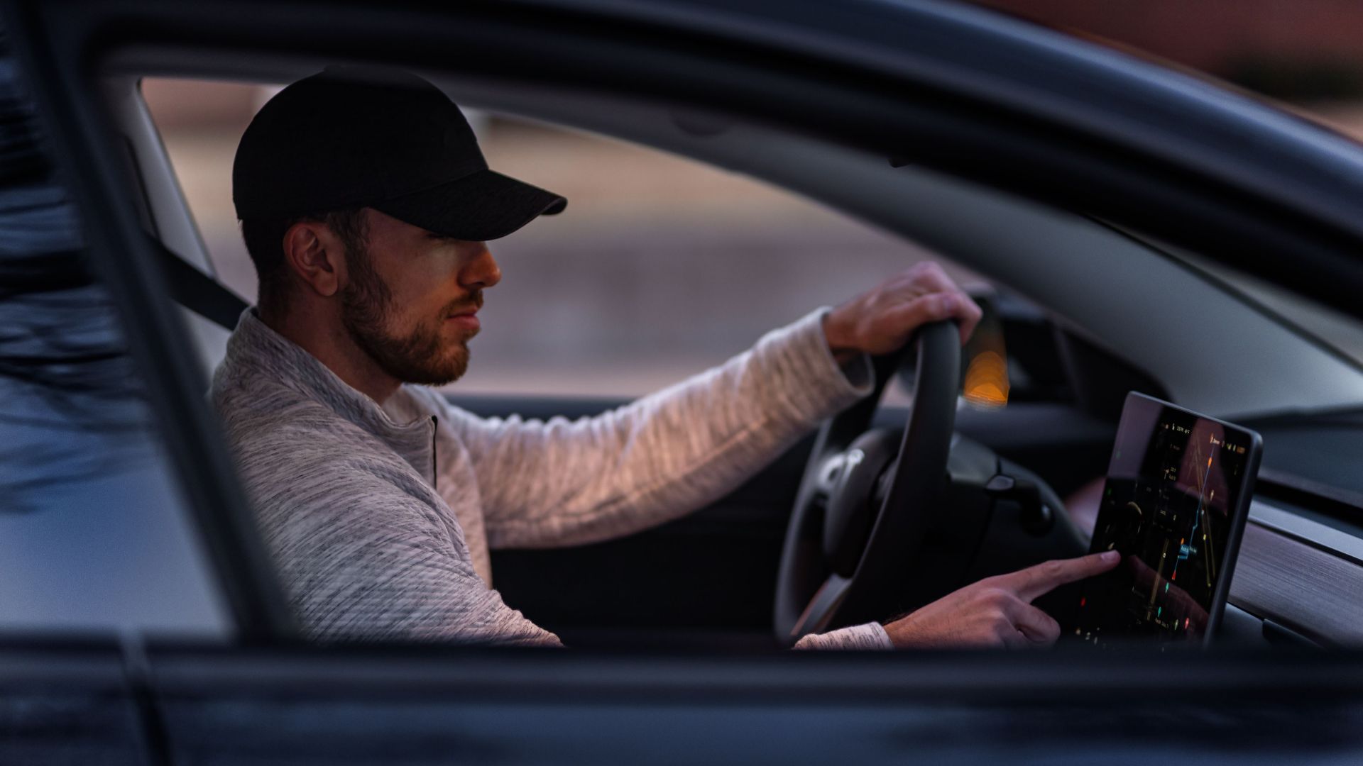 A man interacts with a touchscreen inside an electric car, driving through Dallas, TX.