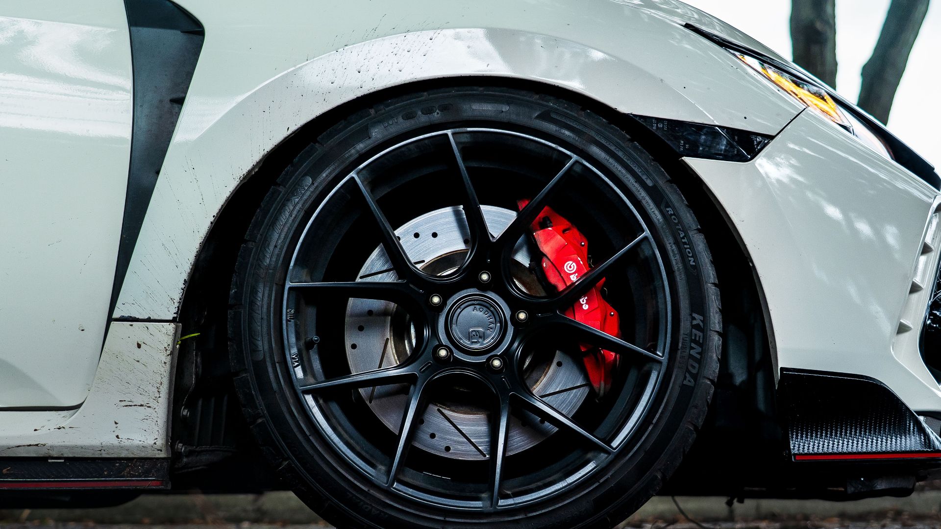 Detailed shot of a car's wheel with alloy rim and red brake caliper, showcasing performance and style.