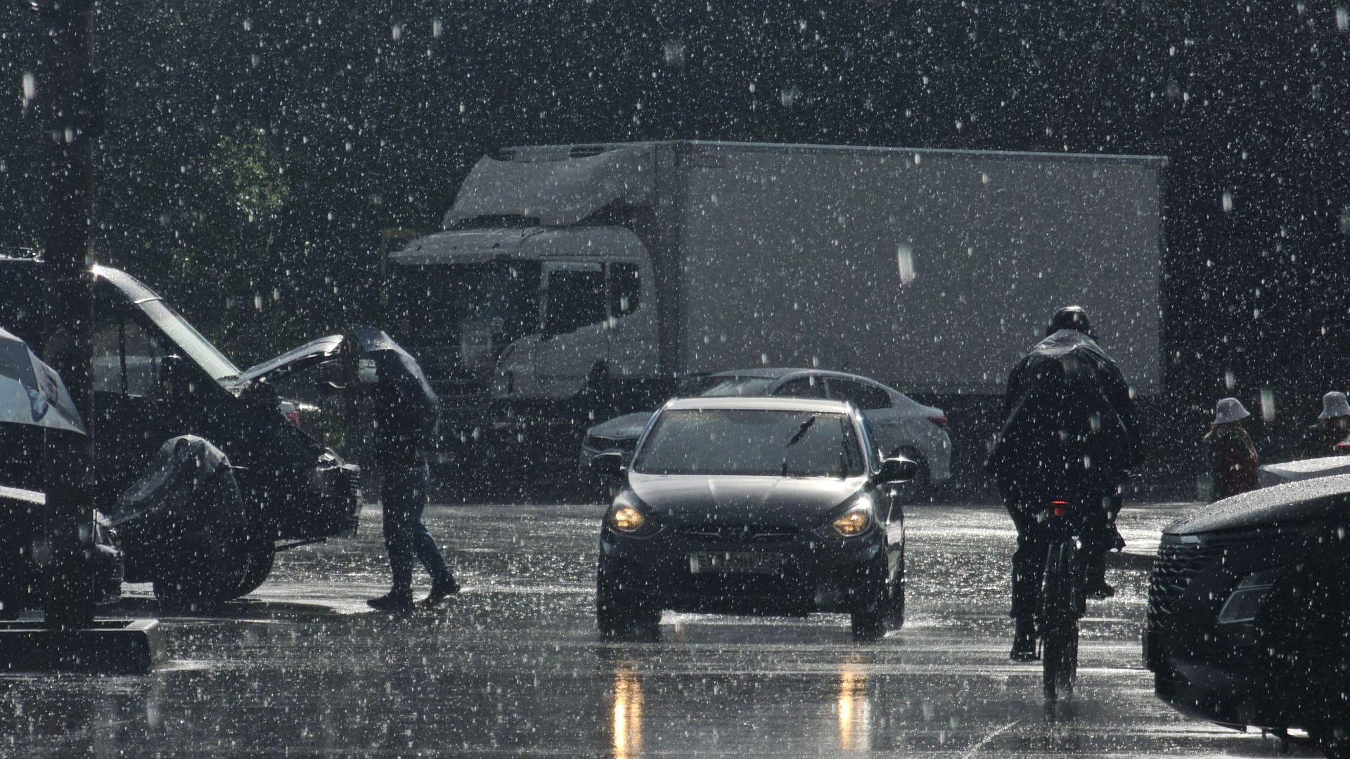 Moody urban street scene in heavy rain with cars and pedestrians.