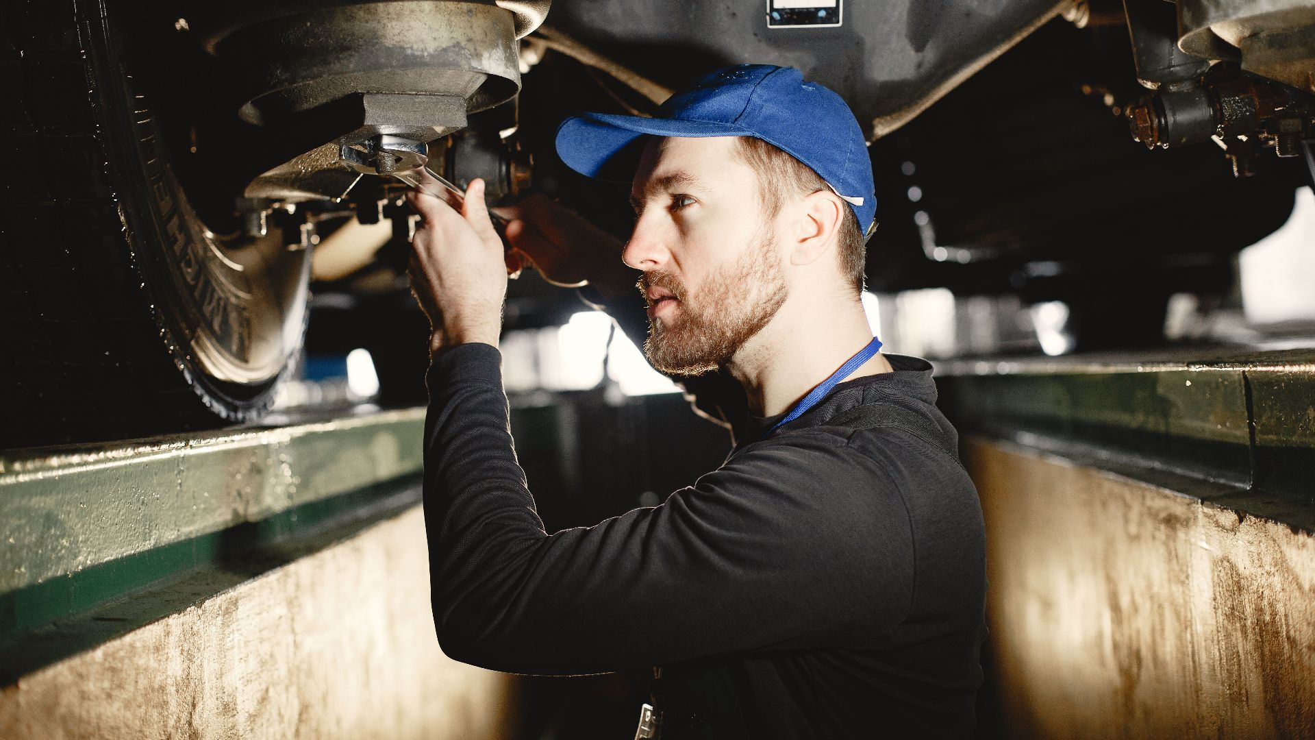 Auto mechanic working diligently on vehicle in workshop setting. Expertise in repair and maintenance.