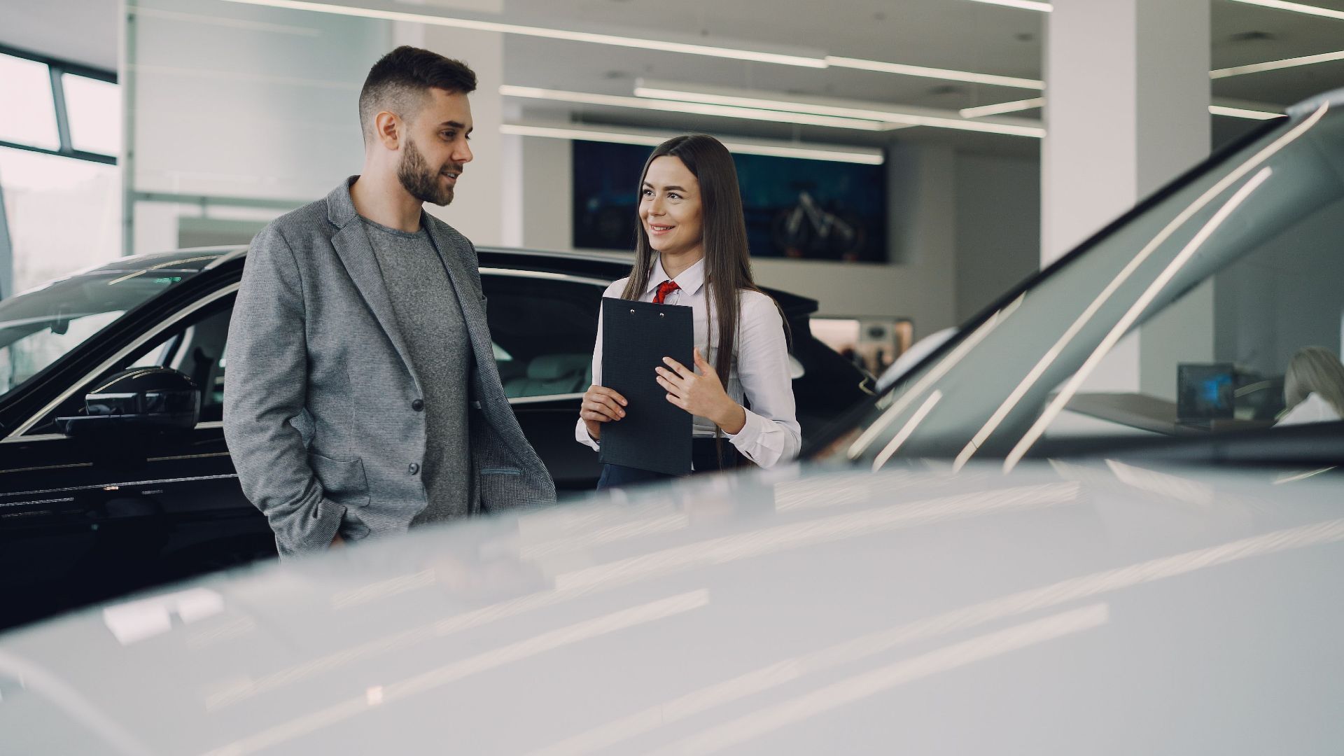 Man consults with salesperson in modern car dealership showroom.