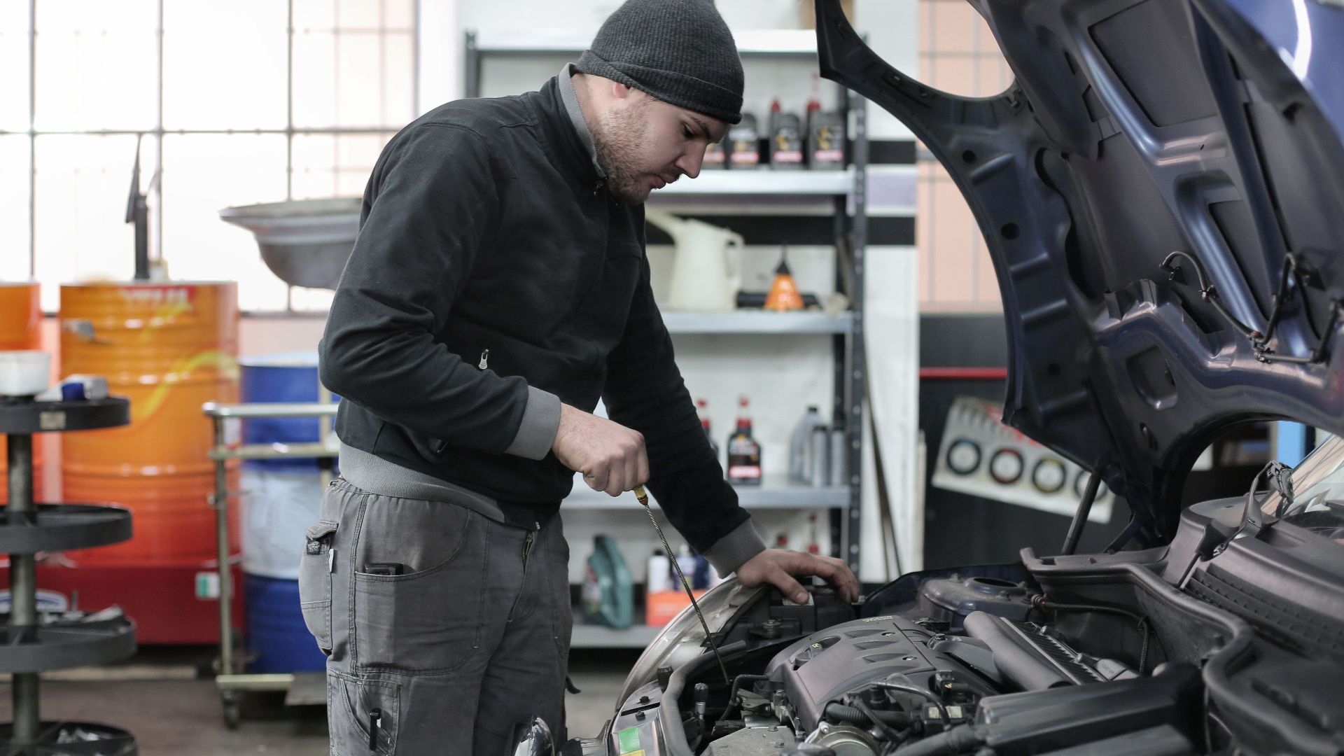 Mechanic checking a car engine in a garage, ensuring quality maintenance and repair.