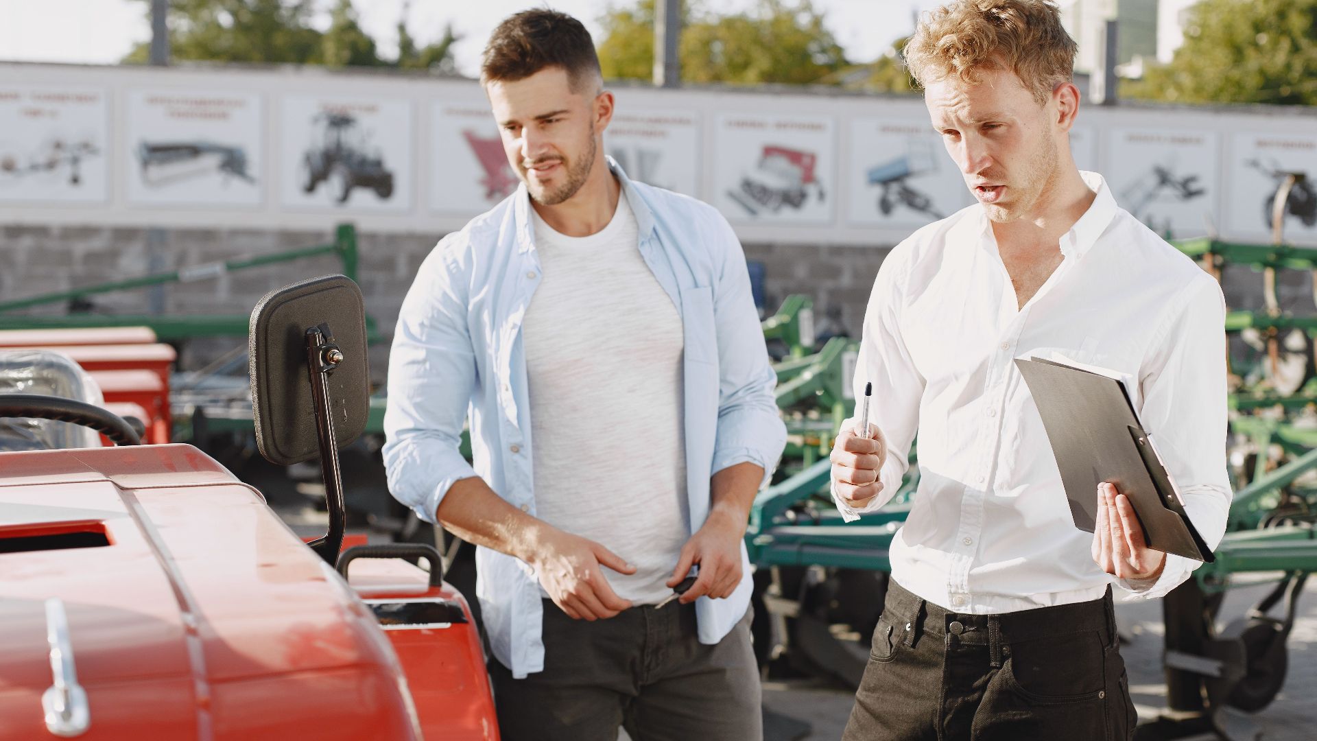 Two men engaging in a discussion about a tractor sale at an outdoor dealership.