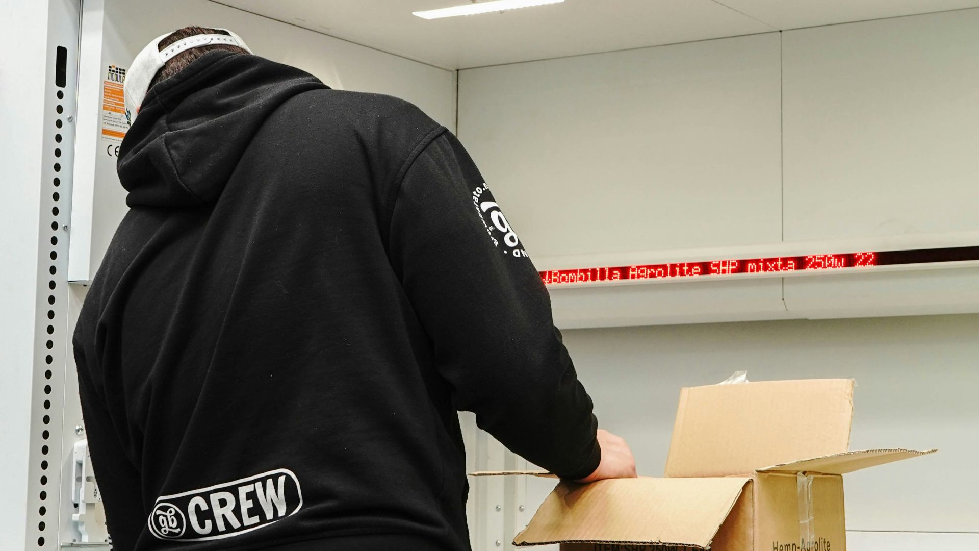 Person preparing a cardboard box on a warehouse conveyor system