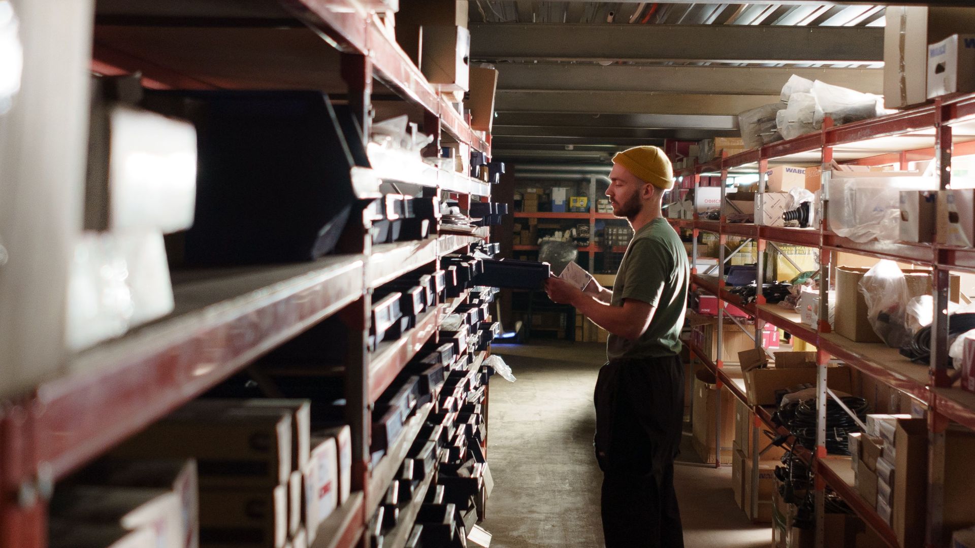 A warehouse worker sorting items on shelves in an organized storage space.