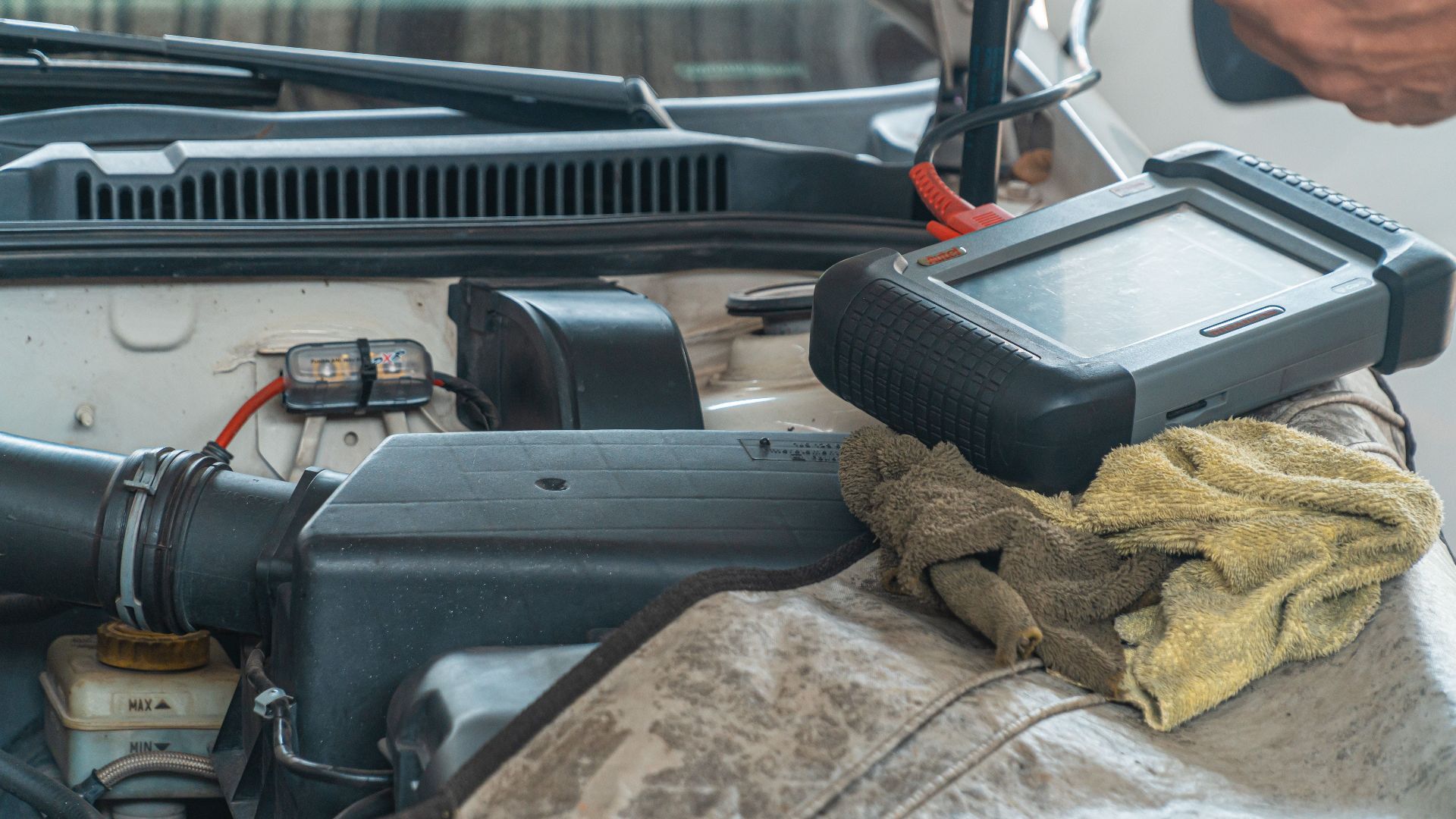 Close-up of a car engine inspection using a diagnostic tool in a garage setting, showcasing automotive maintenance and repair.