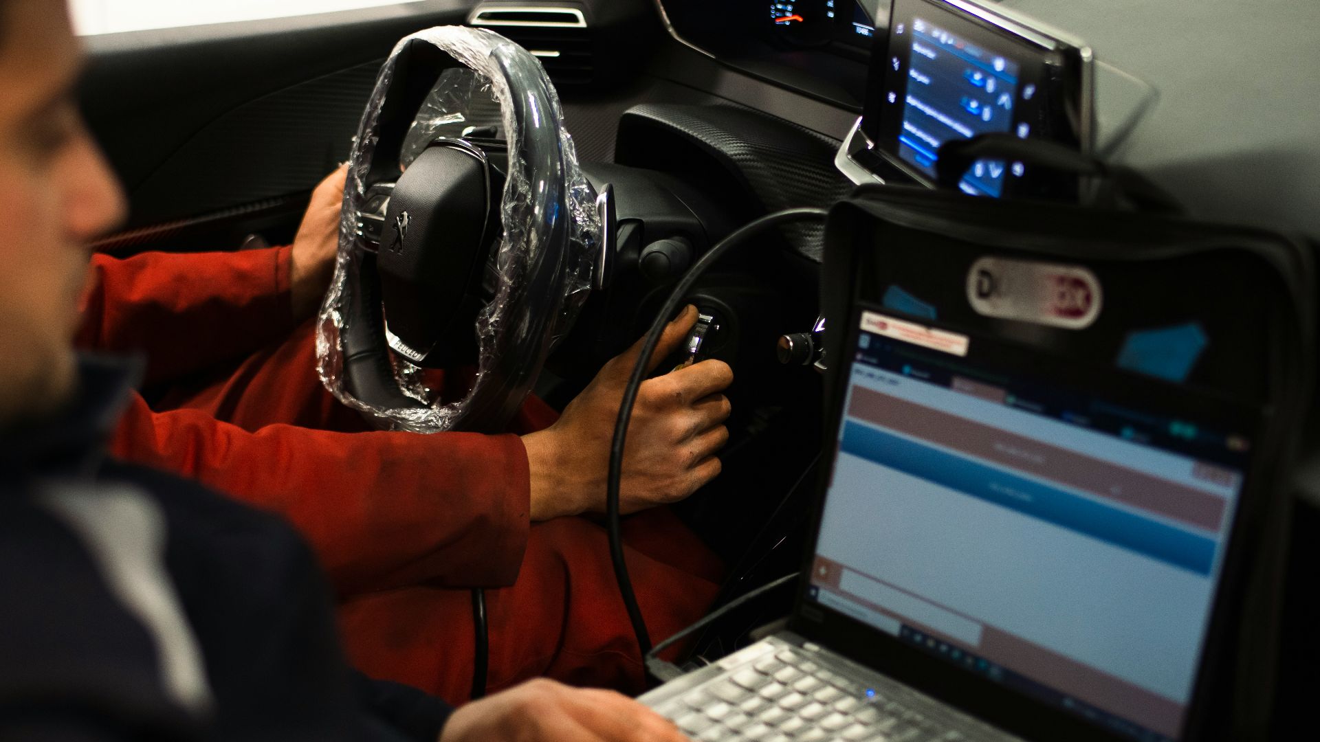 A man sitting in a car using a laptop computer