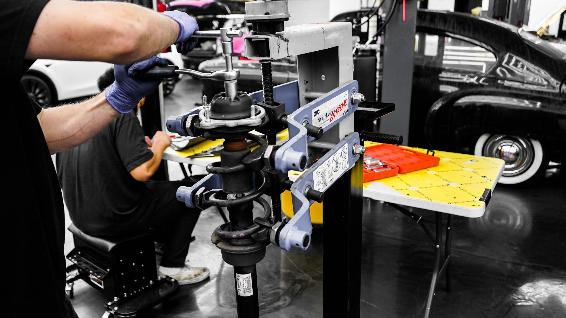 Mechanics using specialized equipment to repair vehicles in an automotive workshop.