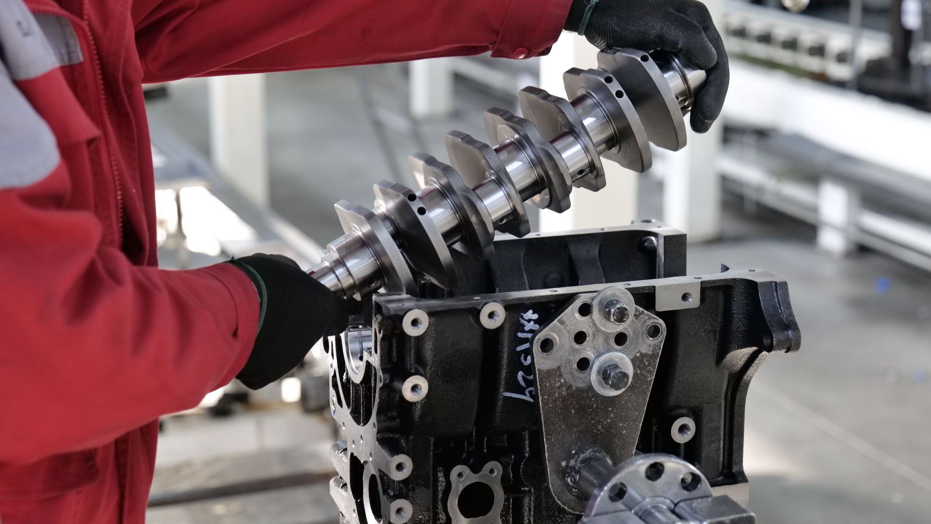 Mechanic working on a crankshaft installation in an engine block in an industrial setting.