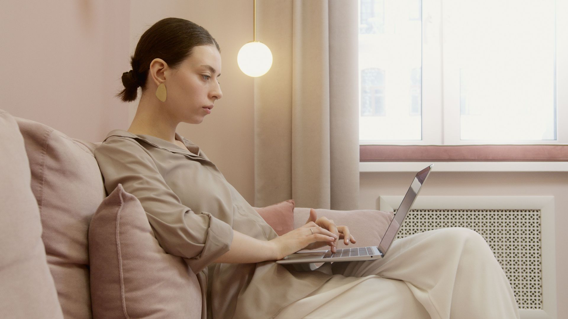 Stylish woman working remotely from her cozy living room, using a laptop.