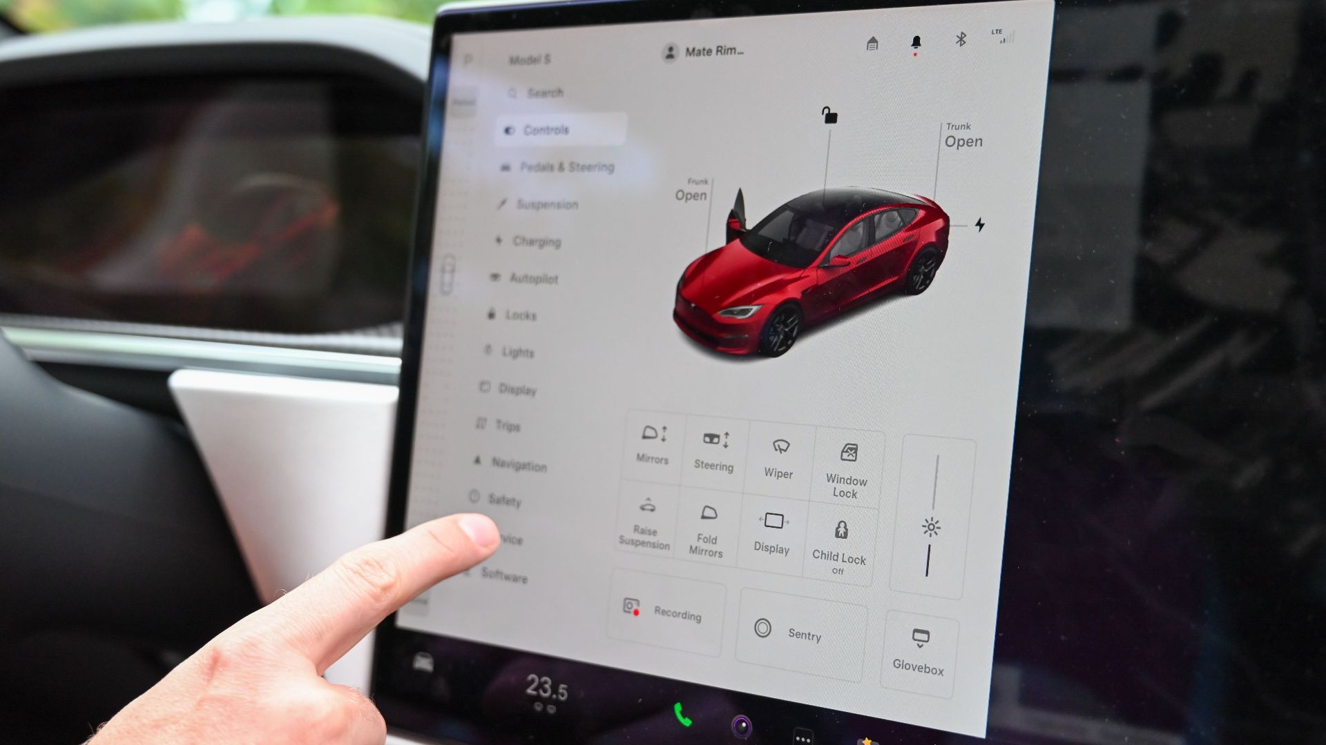 Close-up of a hand interacting with a modern car's touchscreen interface for various controls.