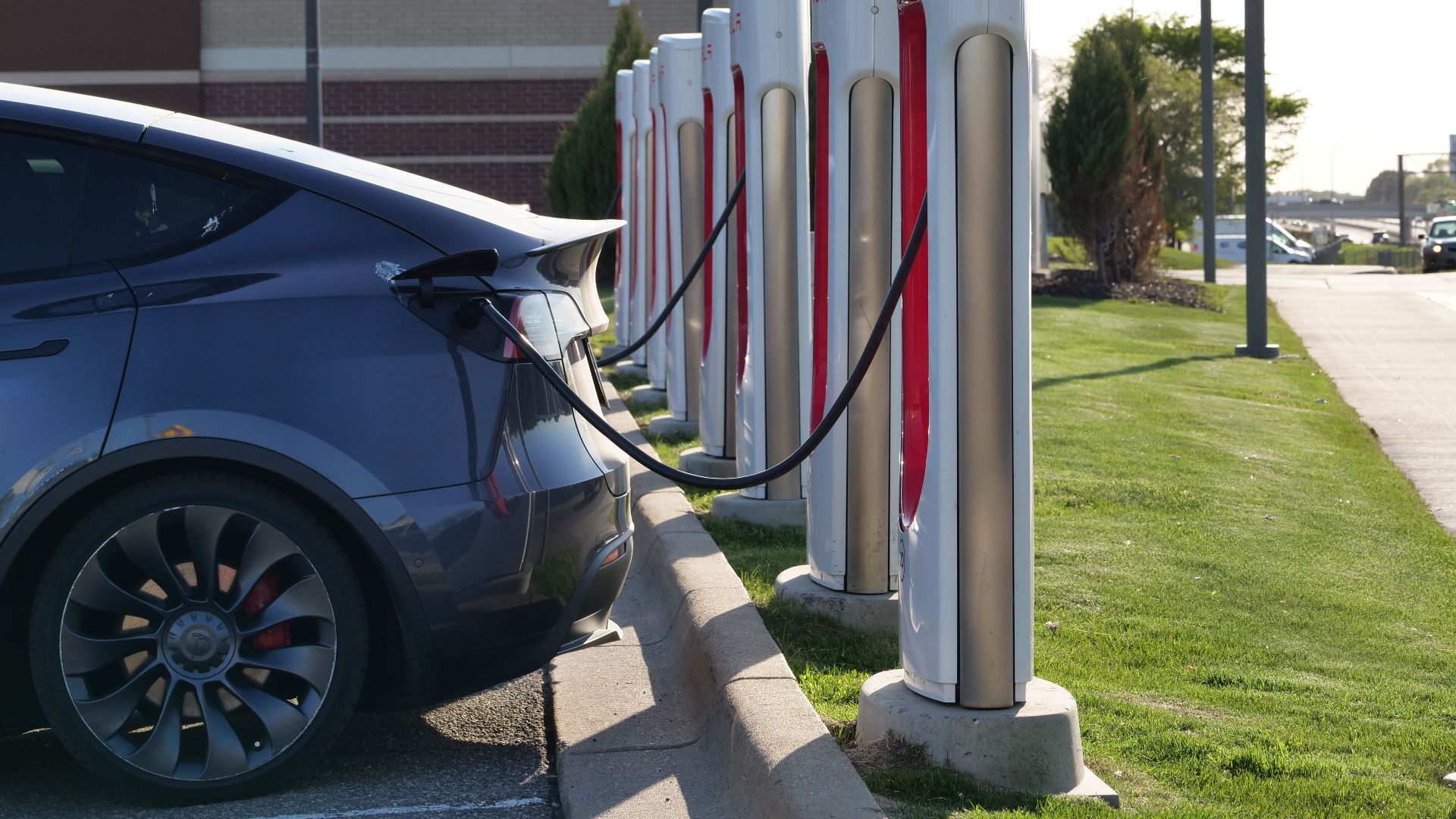 Electric car plugged into a row of charging stations, showcasing modern EV infrastructure.