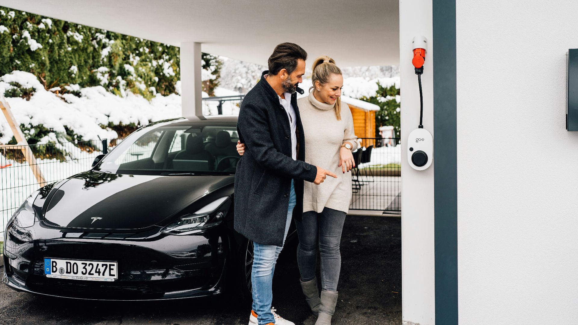 Couple by their electric car next to a charger