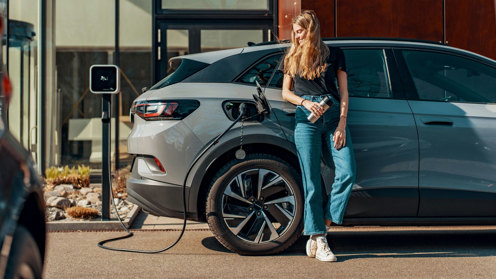 a woman standing next to a blue car