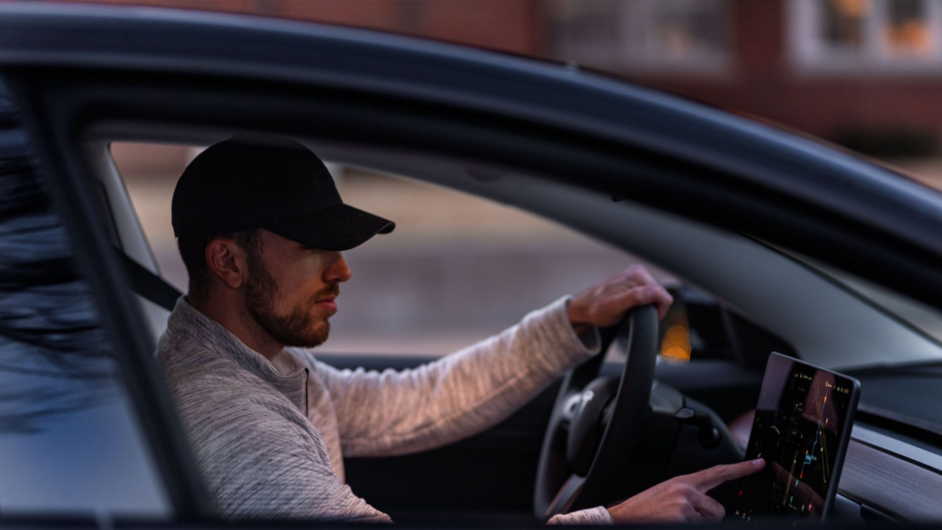 A man interacts with a touchscreen inside an electric car, driving through Dallas, TX.