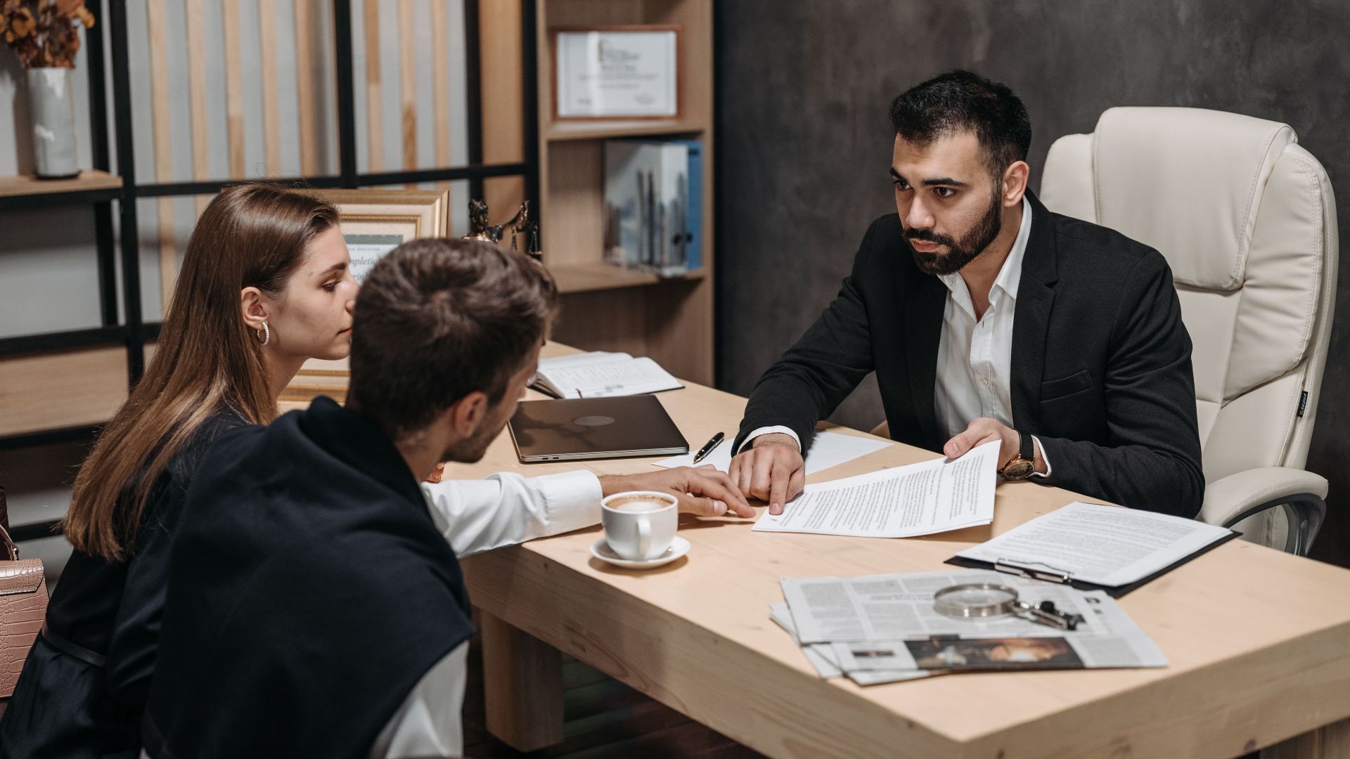 Lawyer discussing legal documents with clients at office desk.