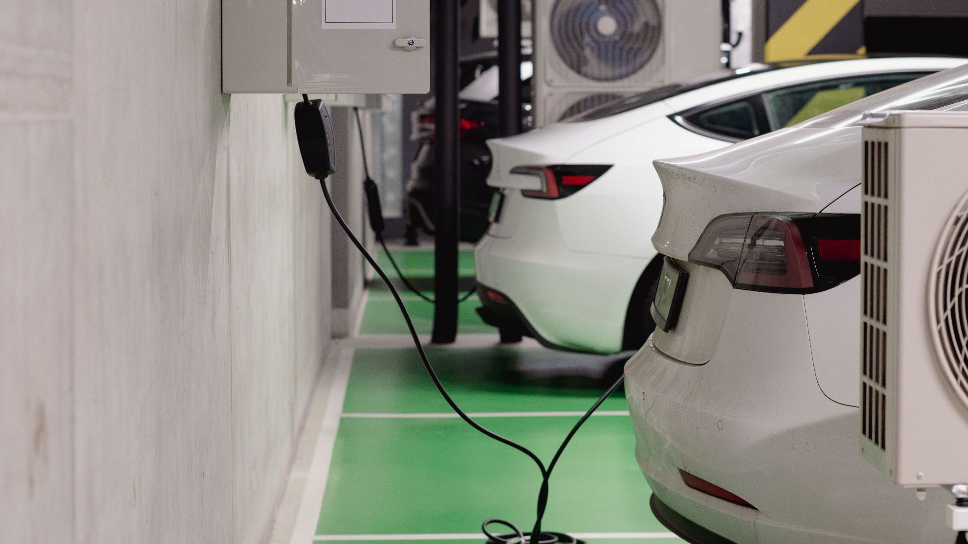 Electric vehicles charging at an indoor station in a modern underground garage.