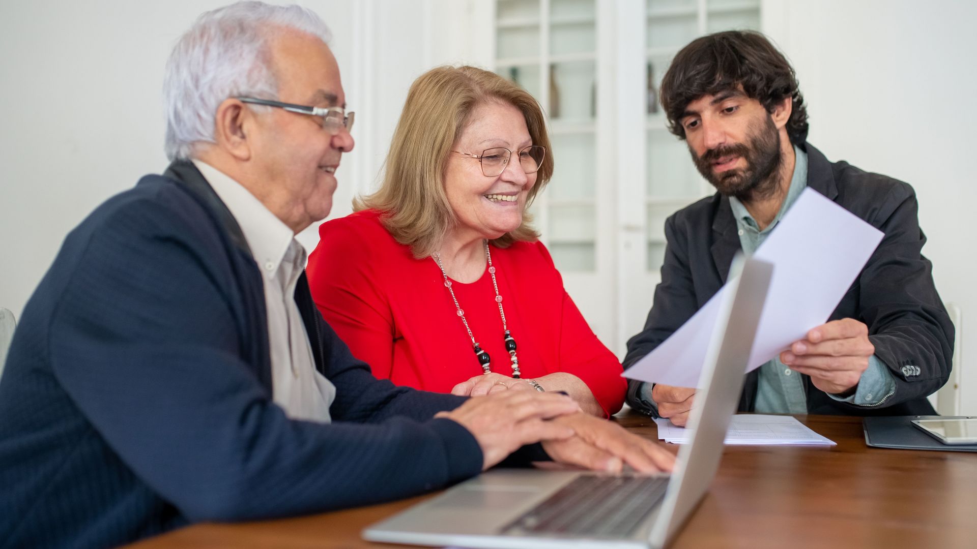 Diverse group discussing documents around a laptop indoors, showcasing teamwork and collaboration.