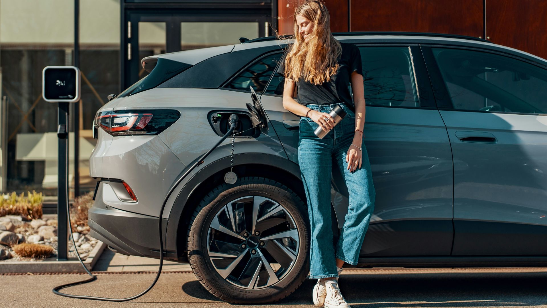 a woman standing next to a blue car