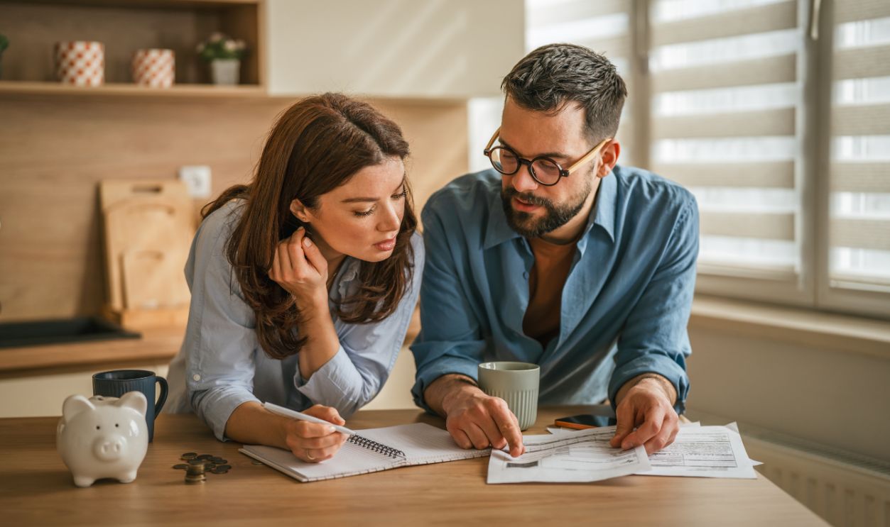 Shutterstock-2743211903, Couple reviewing paperwork and checking numbers together on a kitchen counter, focusing on household budget, financial planning, and saving money while having coffee