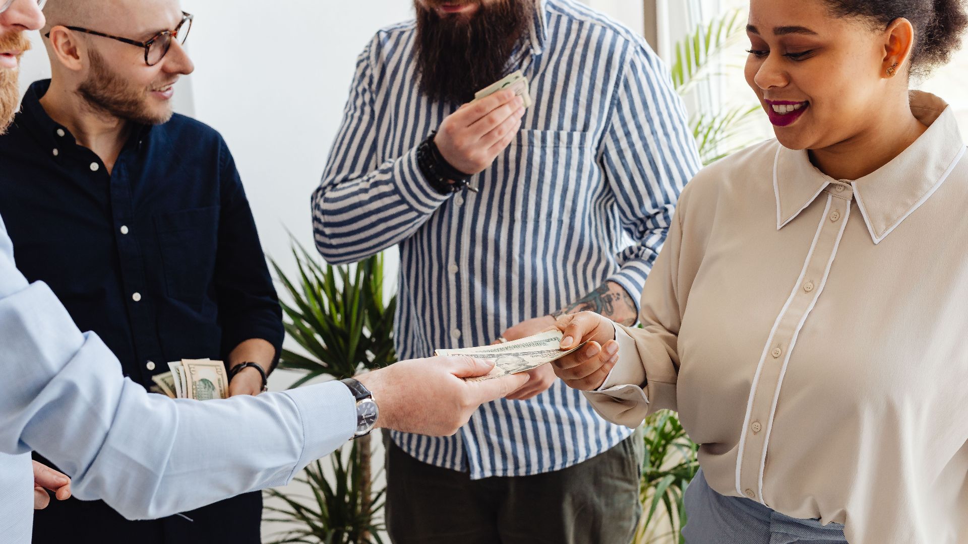 Business professionals exchanging money in a casual office setting.