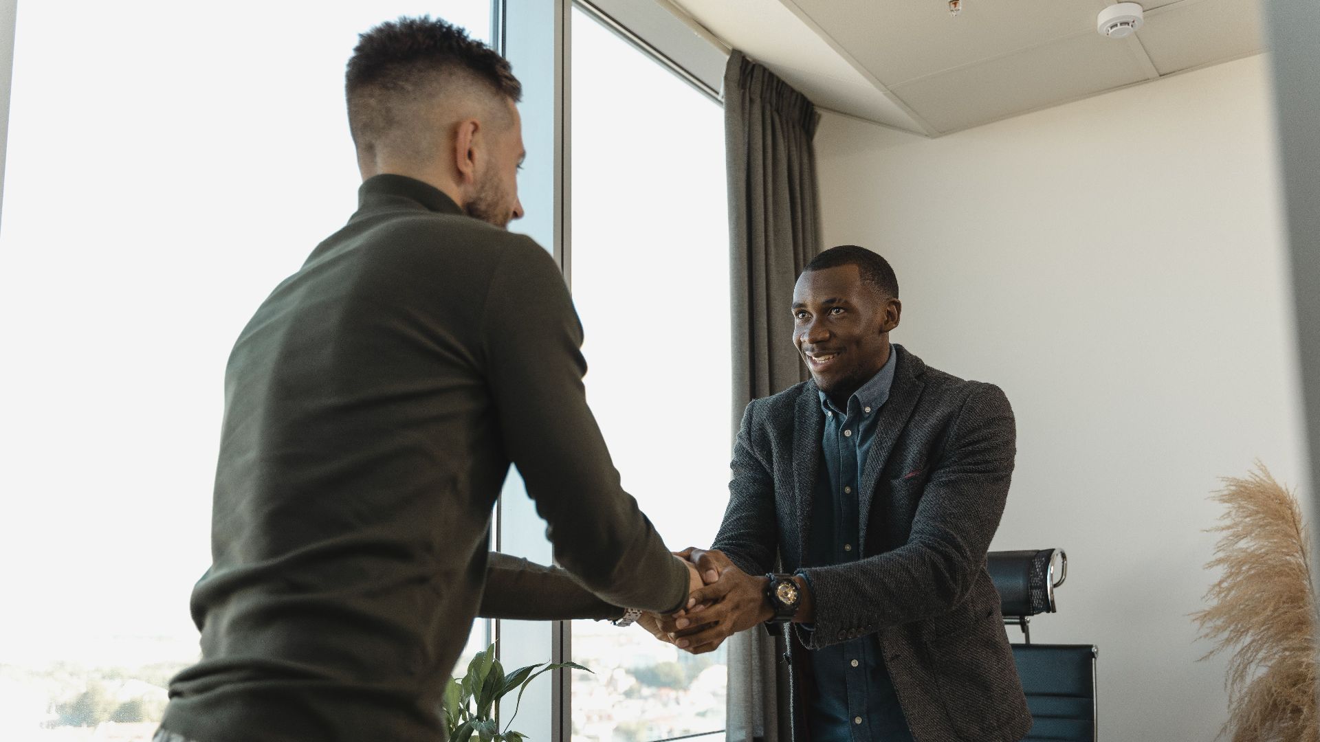 Two businessmen exchanging a handshake during a professional meeting in a modern office setting.