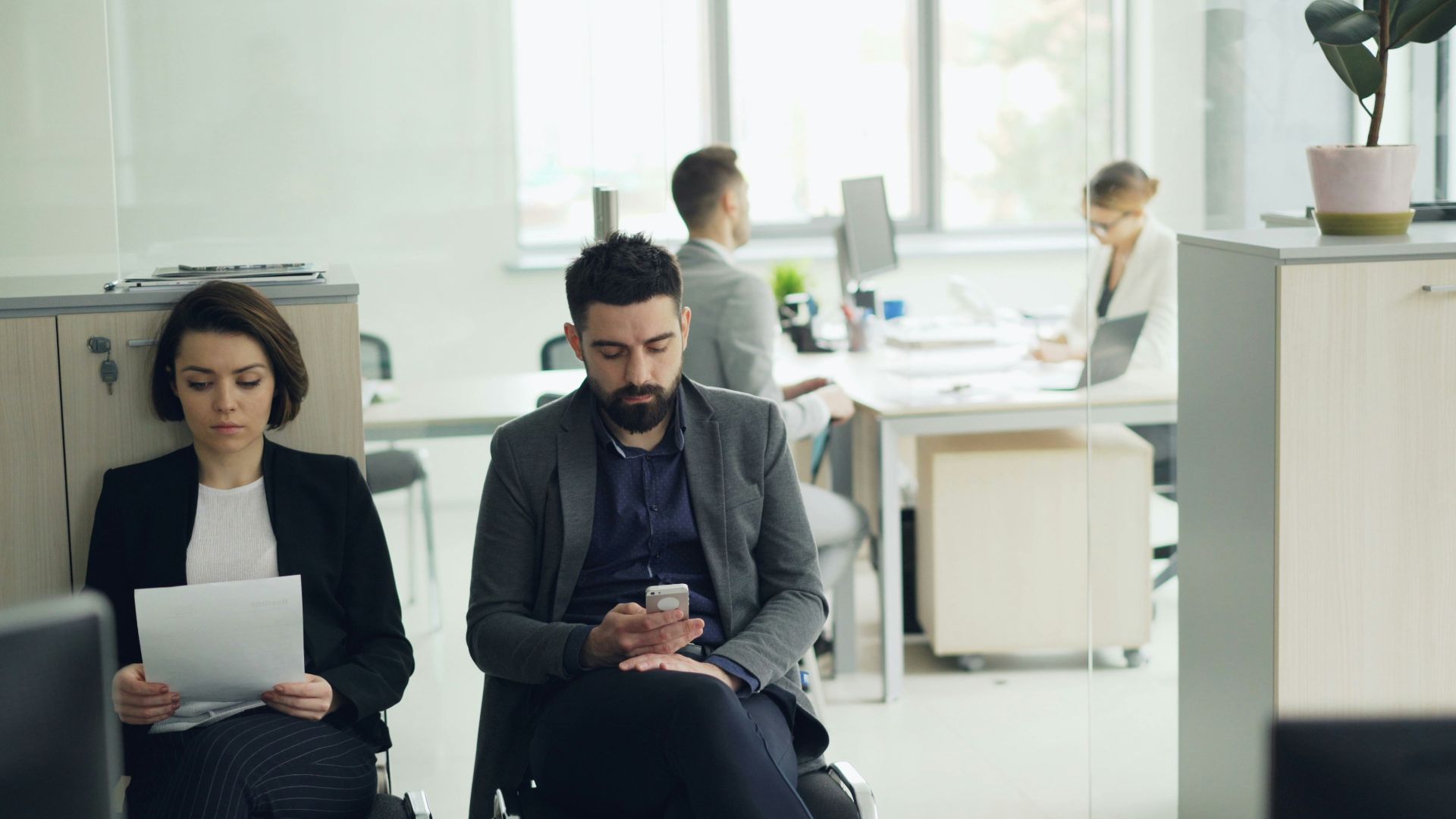 Two people waiting in an office lobby