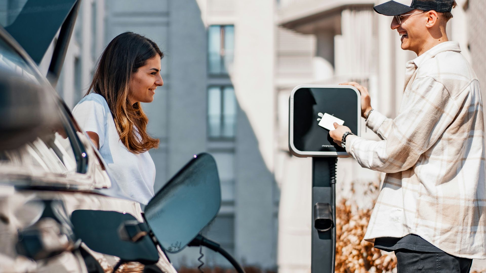 a man and a woman are charging their cars