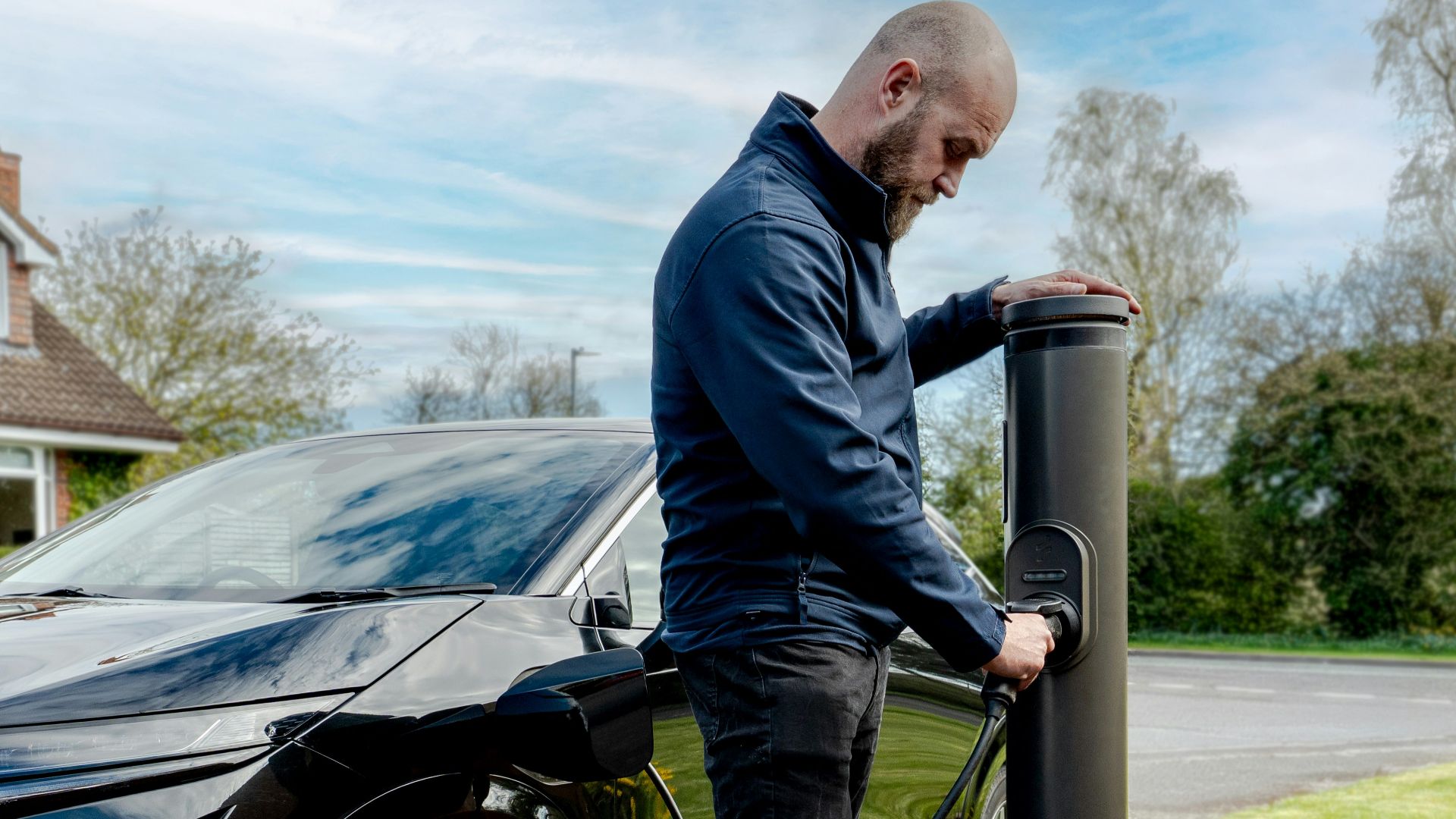 Man charging an electric car at an outdoor station