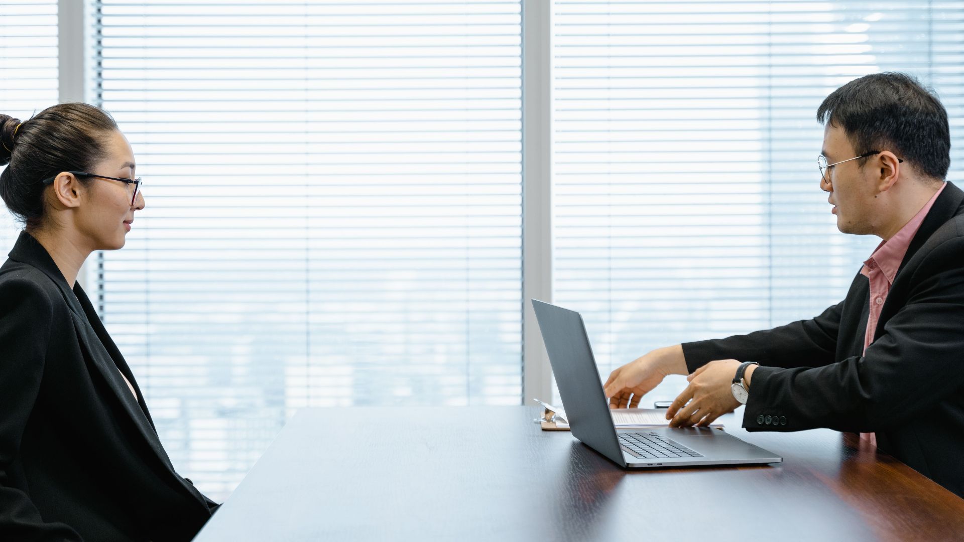 Two professionals engage in a job interview in a modern office. Business attire and corporate environment enhance the scene.