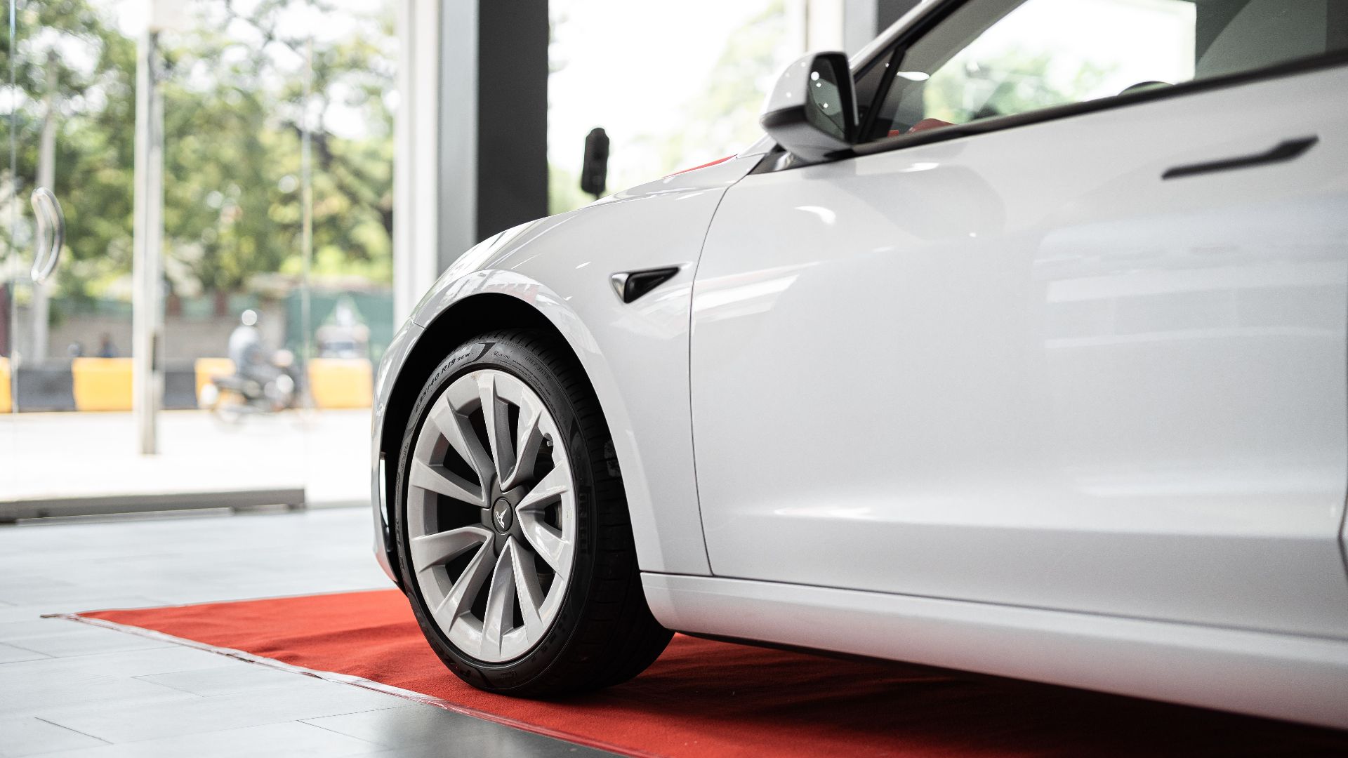 Sleek white electric car on display in a modern showroom on a red carpet.