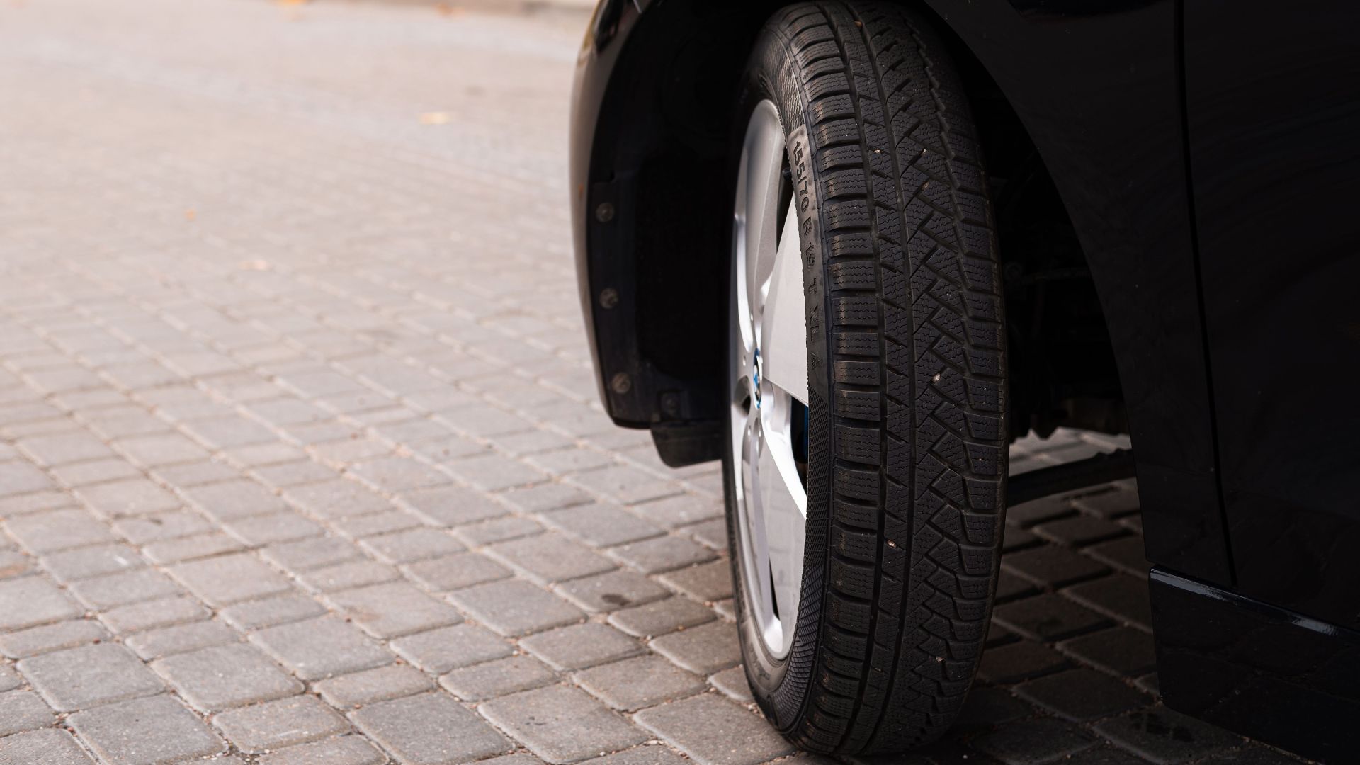 A black car's tire on a cobblestone road captures the essence of urban transportation.