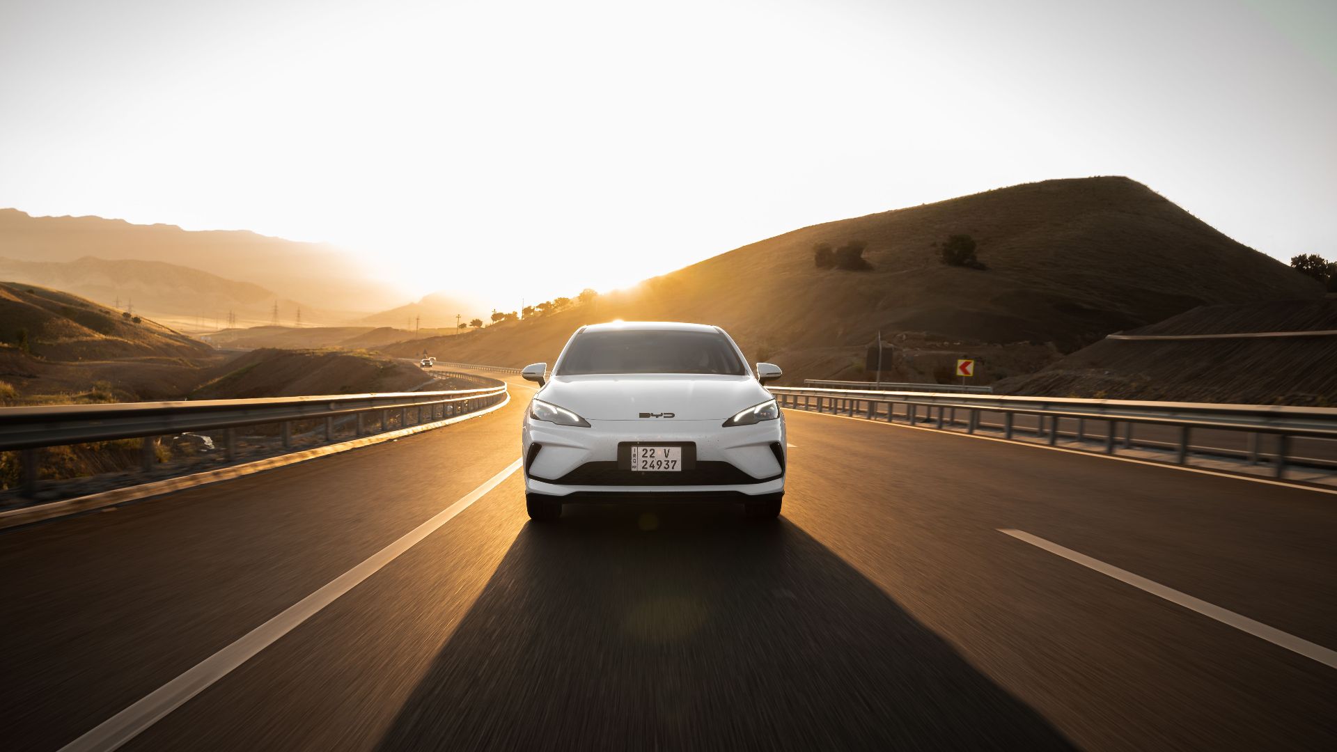 Electric car driving on a scenic highway at sunset, highlighting modern automotive design and sustainable travel.