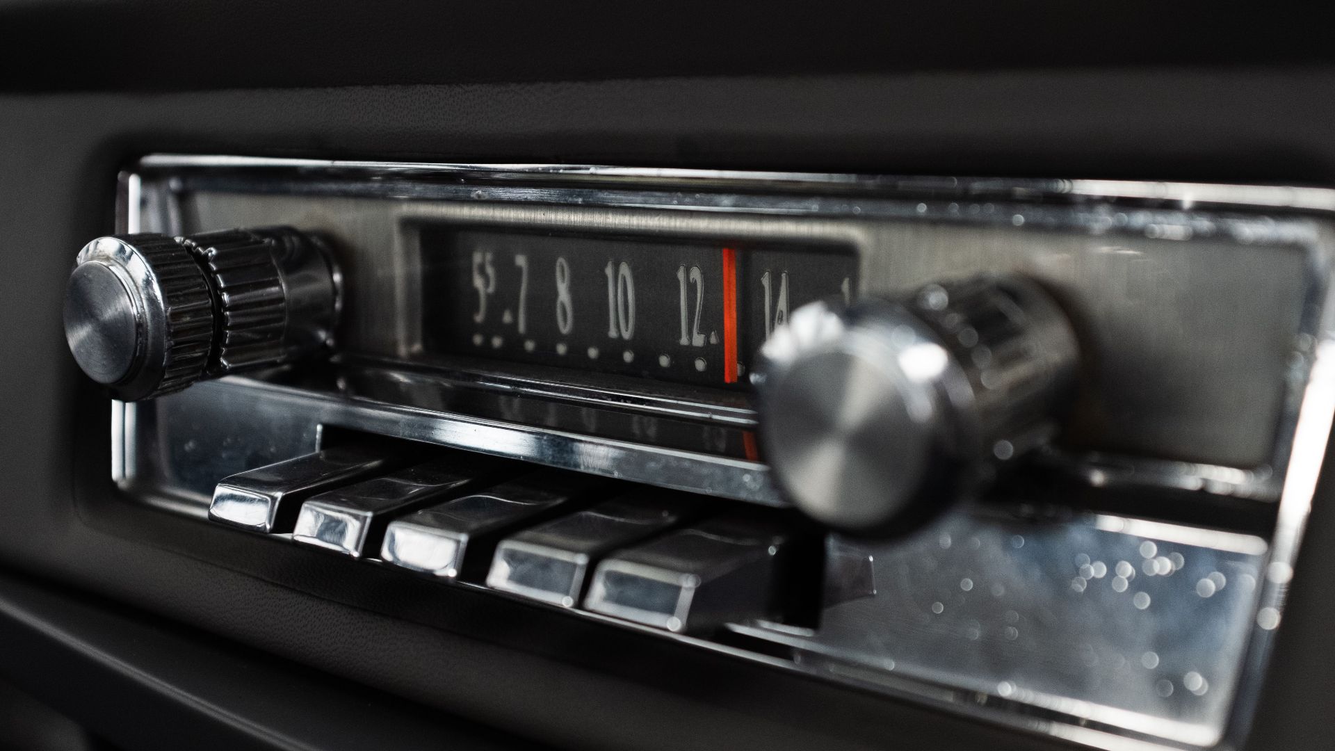 Detailed view of a classic car radio dashboard with chrome knobs and buttons.