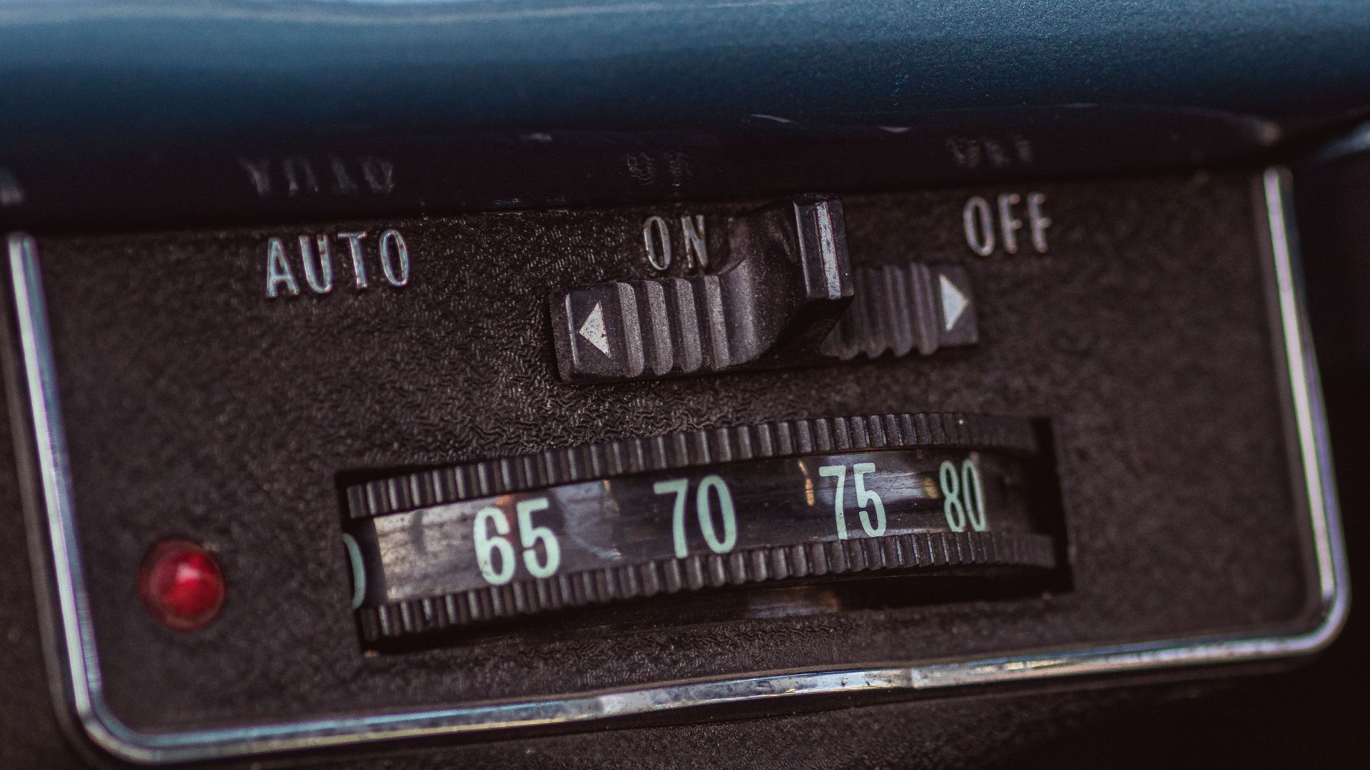 Detailed view of vintage car dashboard showing manual switch and temperature dial from 1960s.